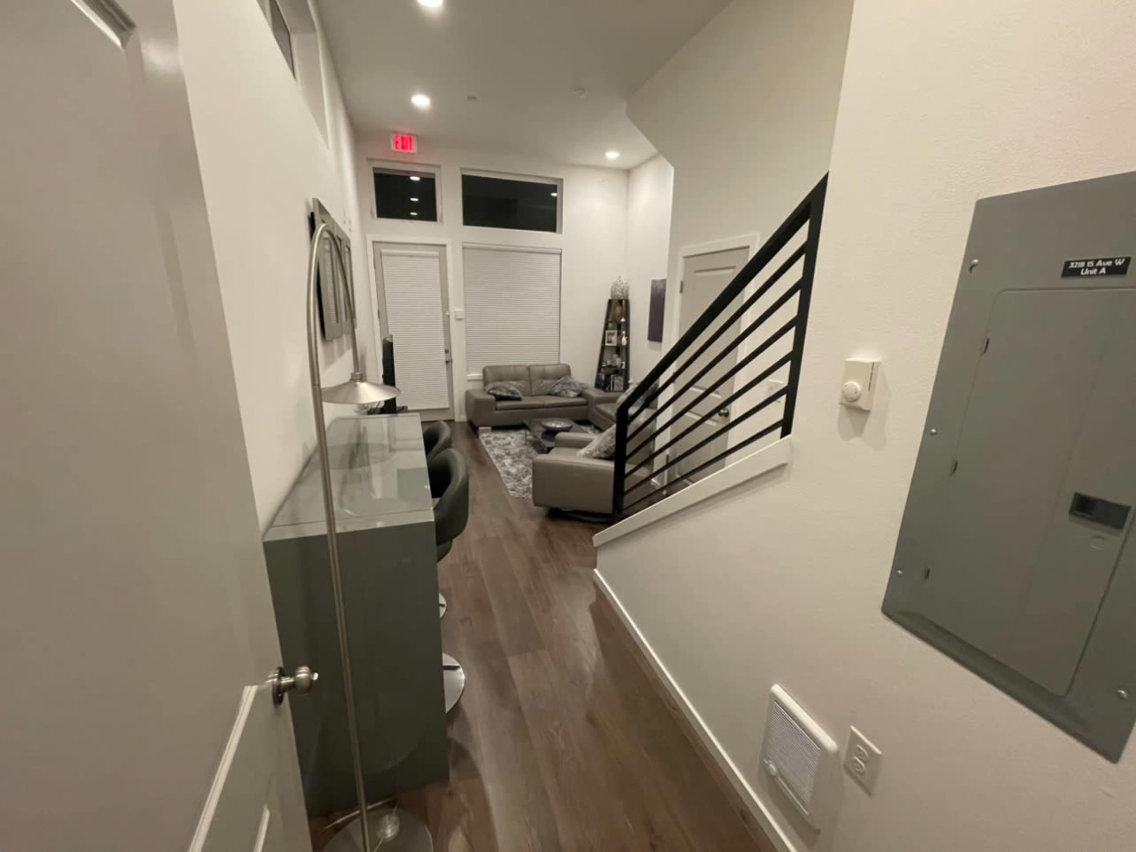 A modern hallway leading to a living area with a staircase on the right and a bar counter on the left.