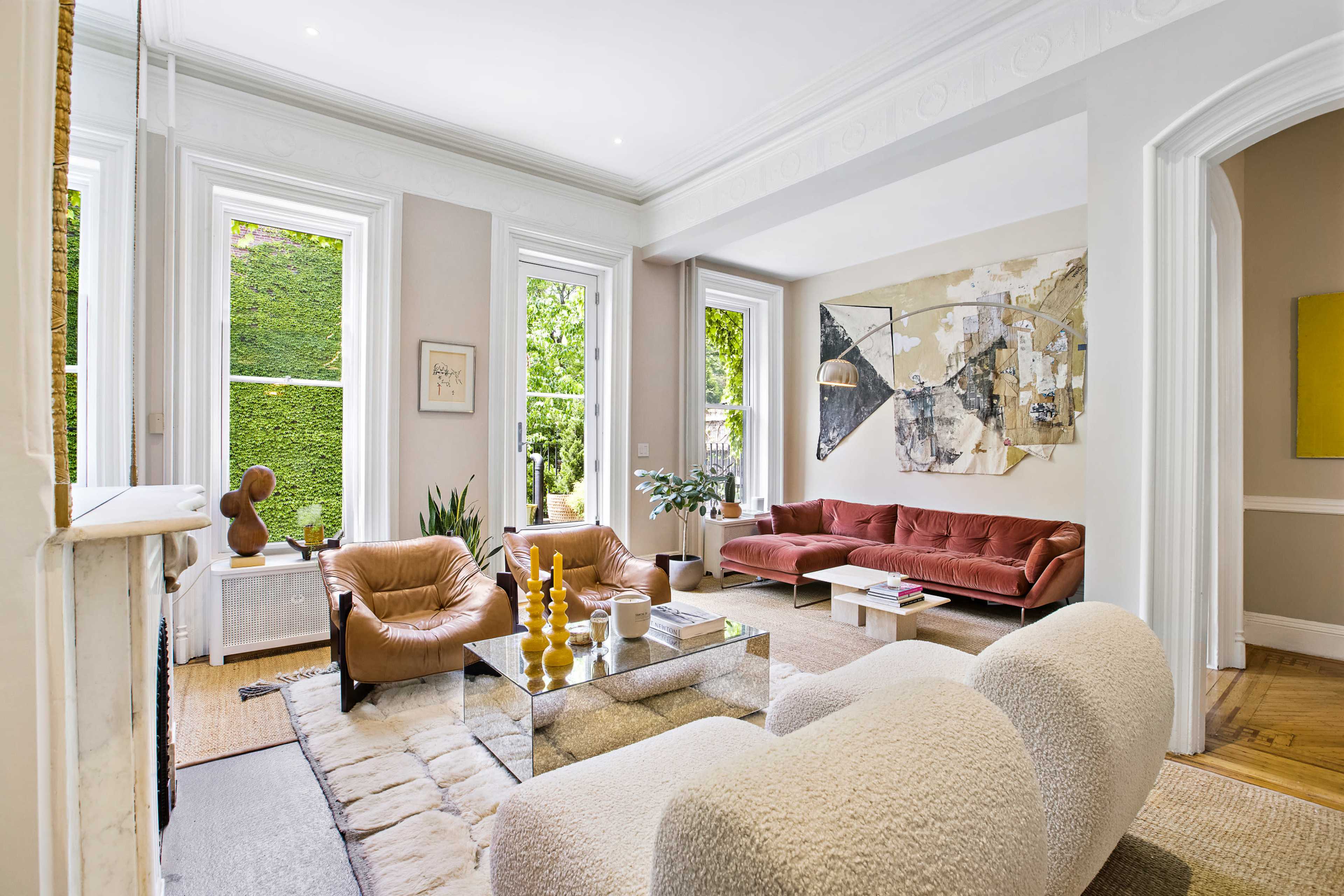 A stylish living room with large windows, modern furniture, and artwork on the walls.