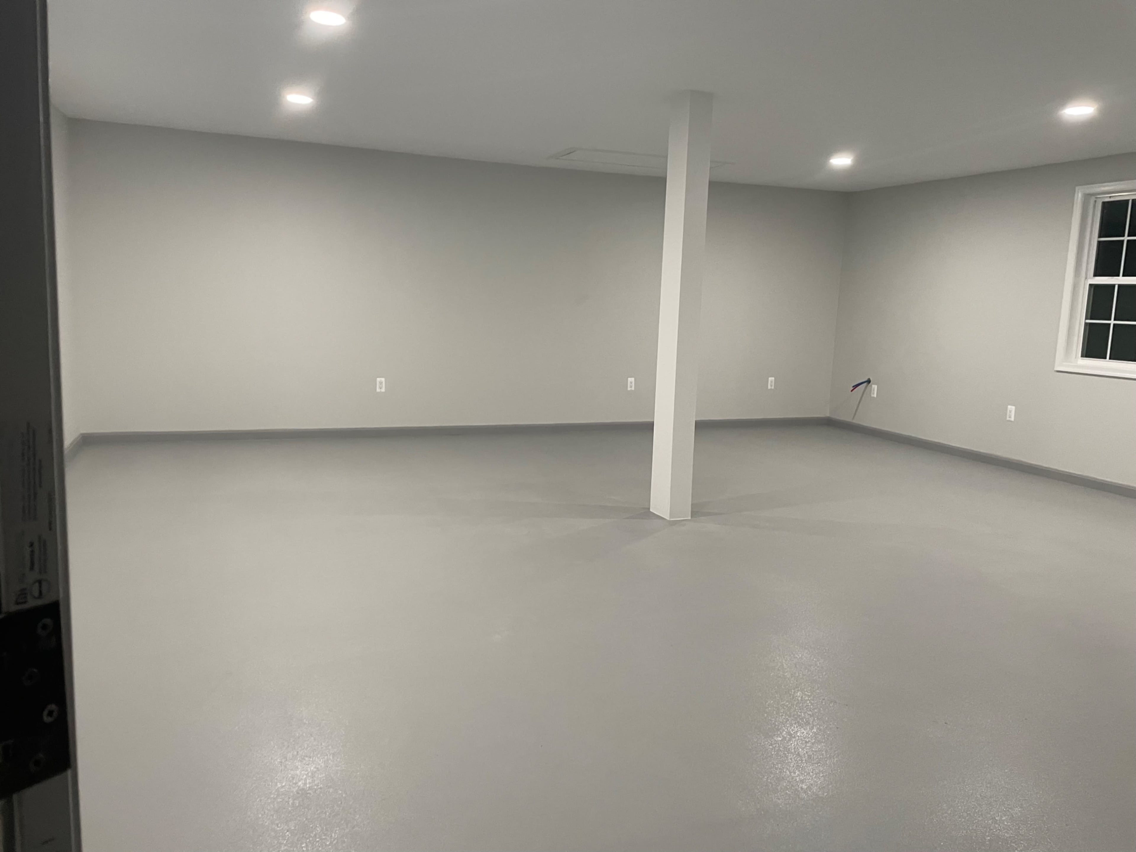 A spacious, empty room with gray walls, a gray floor, and a central support column.