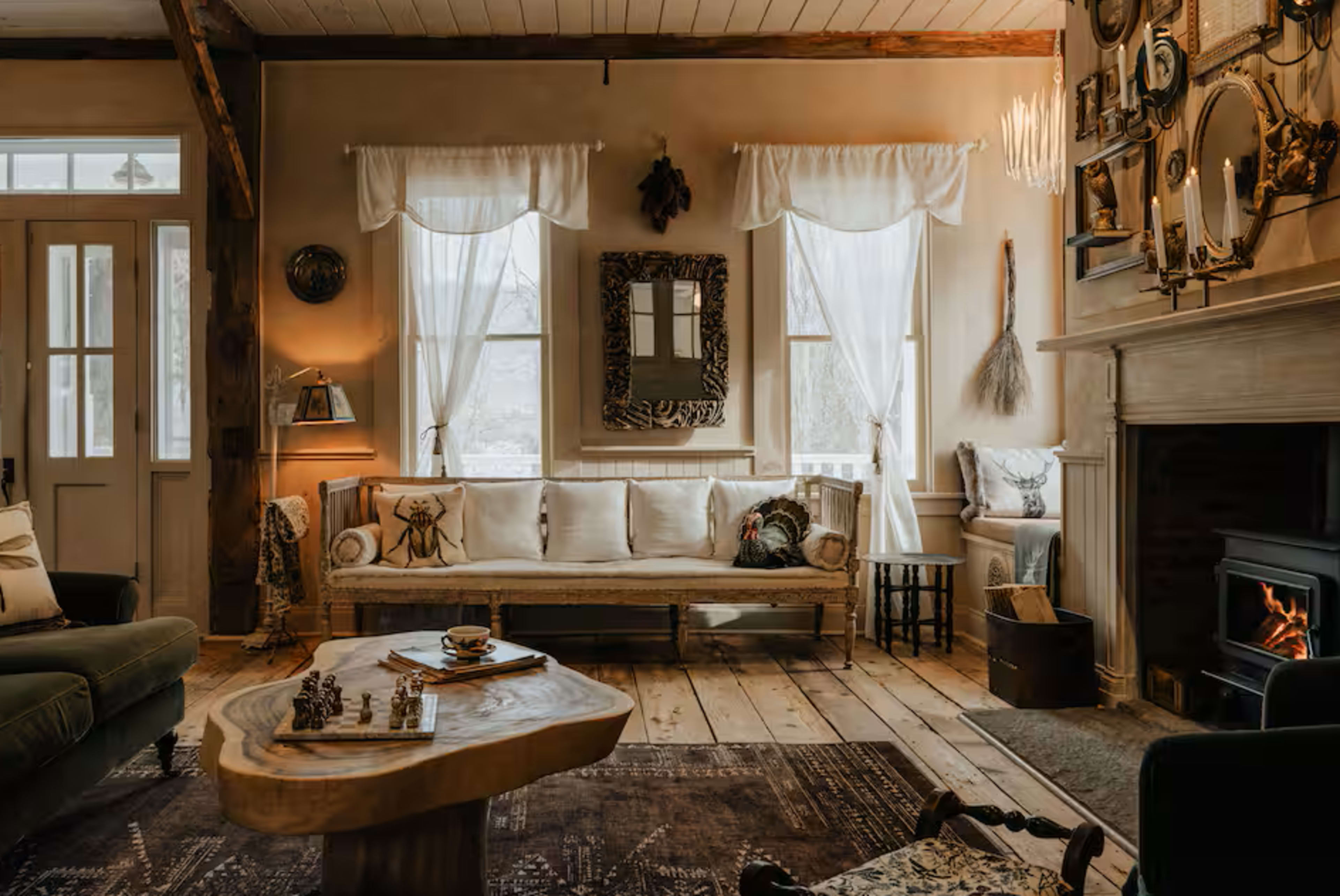 The living room features a cozy arrangement with a wooden coffee table, a patterned rug, a comfortable couch, and large windows allowing natural light to fill the space.