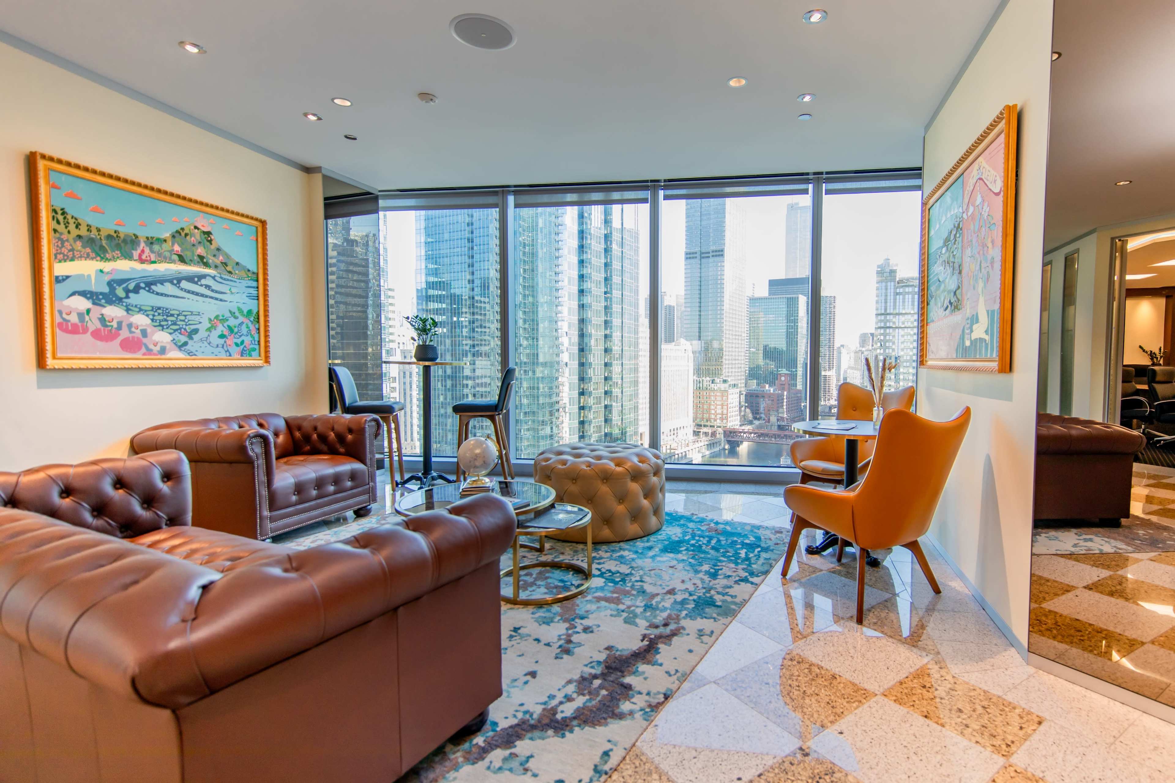 A modern office lounge features brown leather sofas, a glass coffee table, and a view of a city skyline.