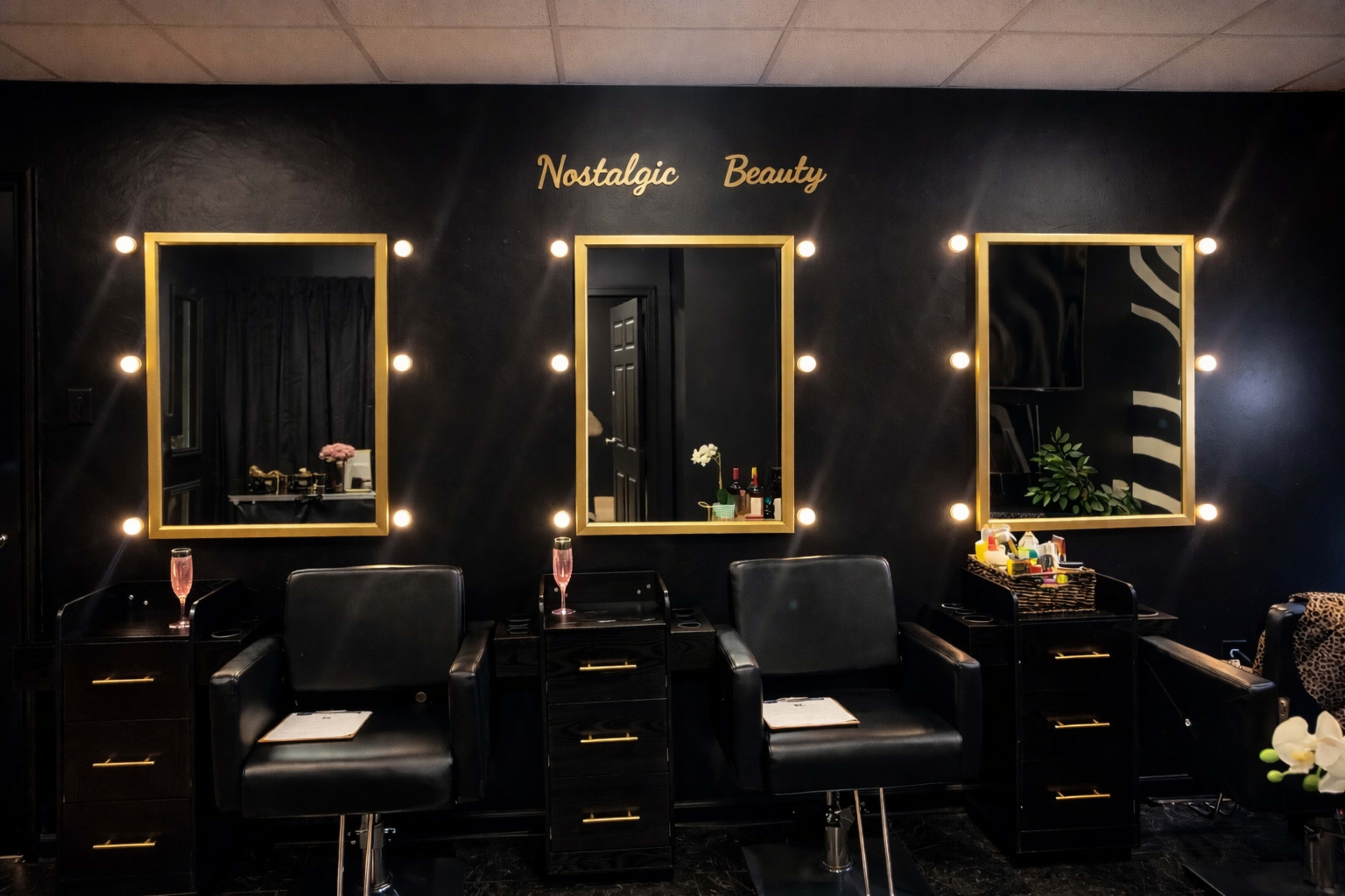 The image shows a beauty salon interior with three illuminated mirrors, black styling chairs, and a wall adorned with the text "Nostalgic Beauty."