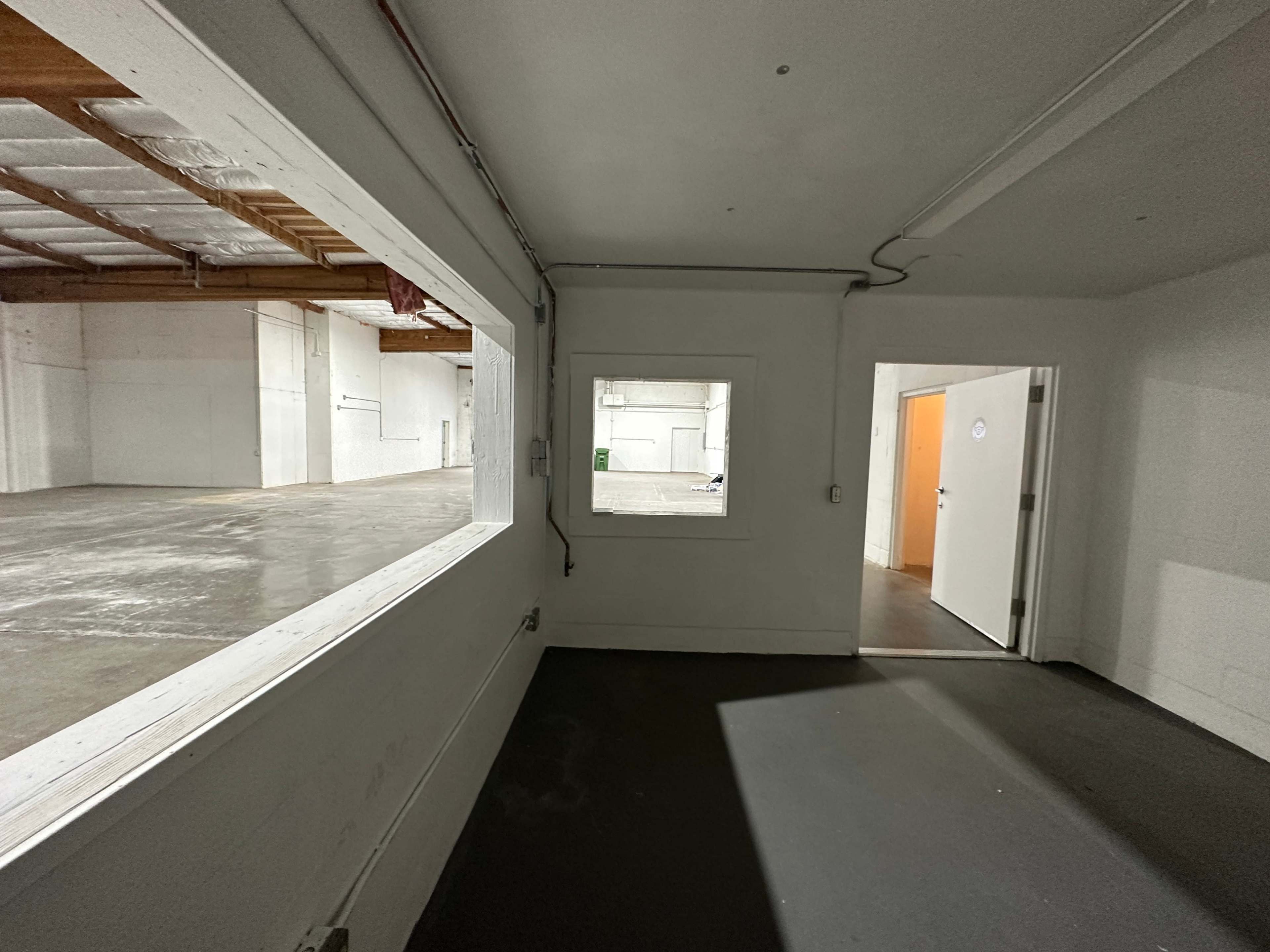 An interior space with two windows and a doorway leading to an adjoining room.