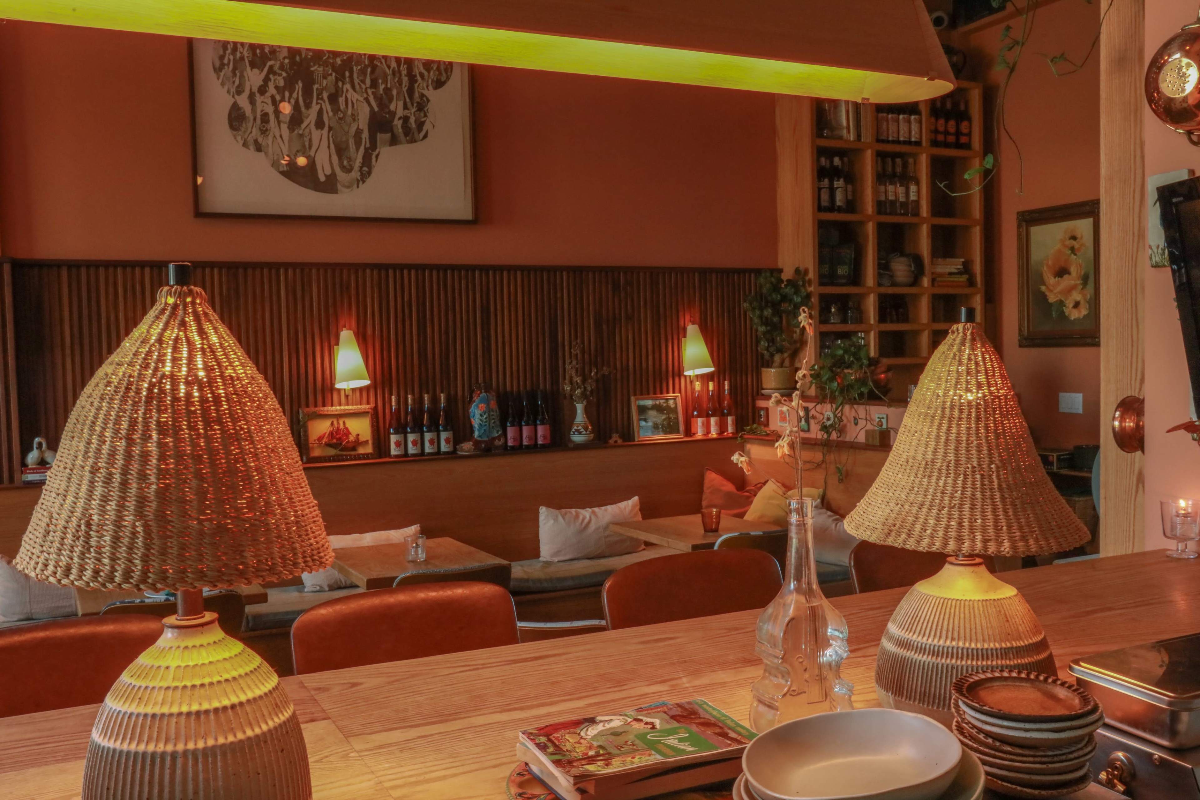 The image shows a cozy interior of a cafe or restaurant featuring warm lighting, wooden furniture, and decorative lamps.