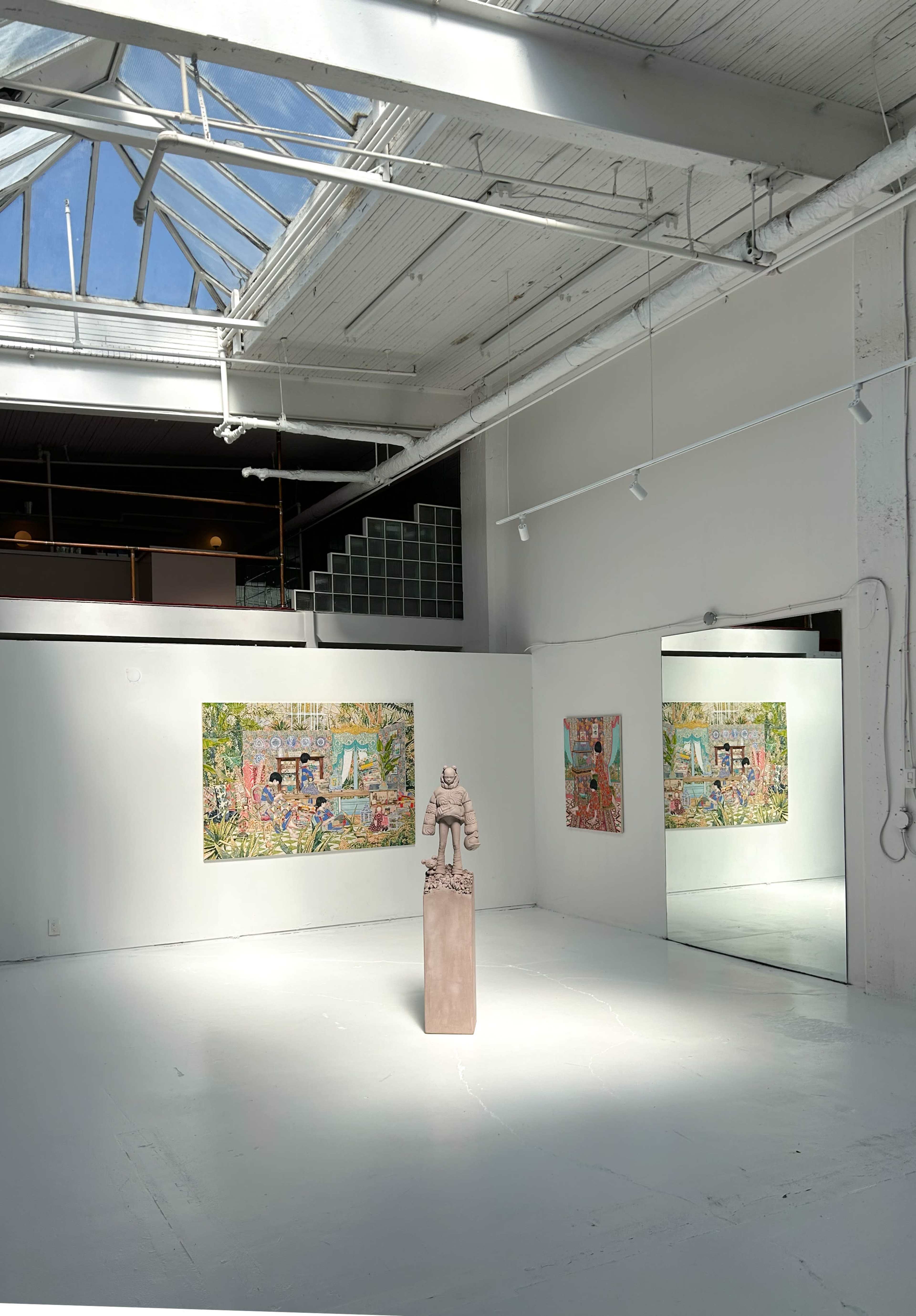 The image shows an art gallery with three colorful artworks displayed on the white walls and a solitary sculpture in the center of the room, illuminated by natural light from a skylight above.