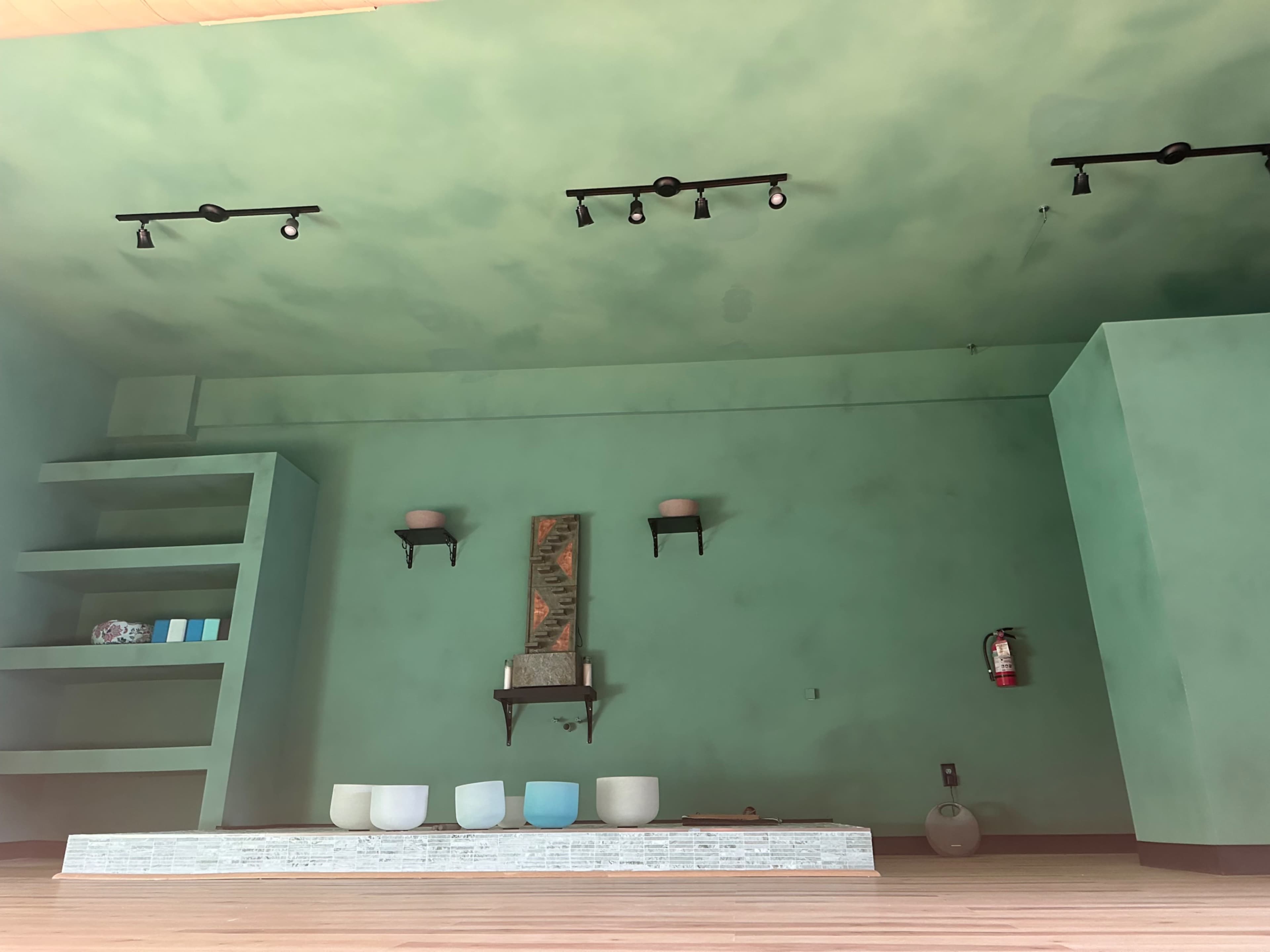 An interior space with green walls, a stone platform at the front, and shelves on the left side.