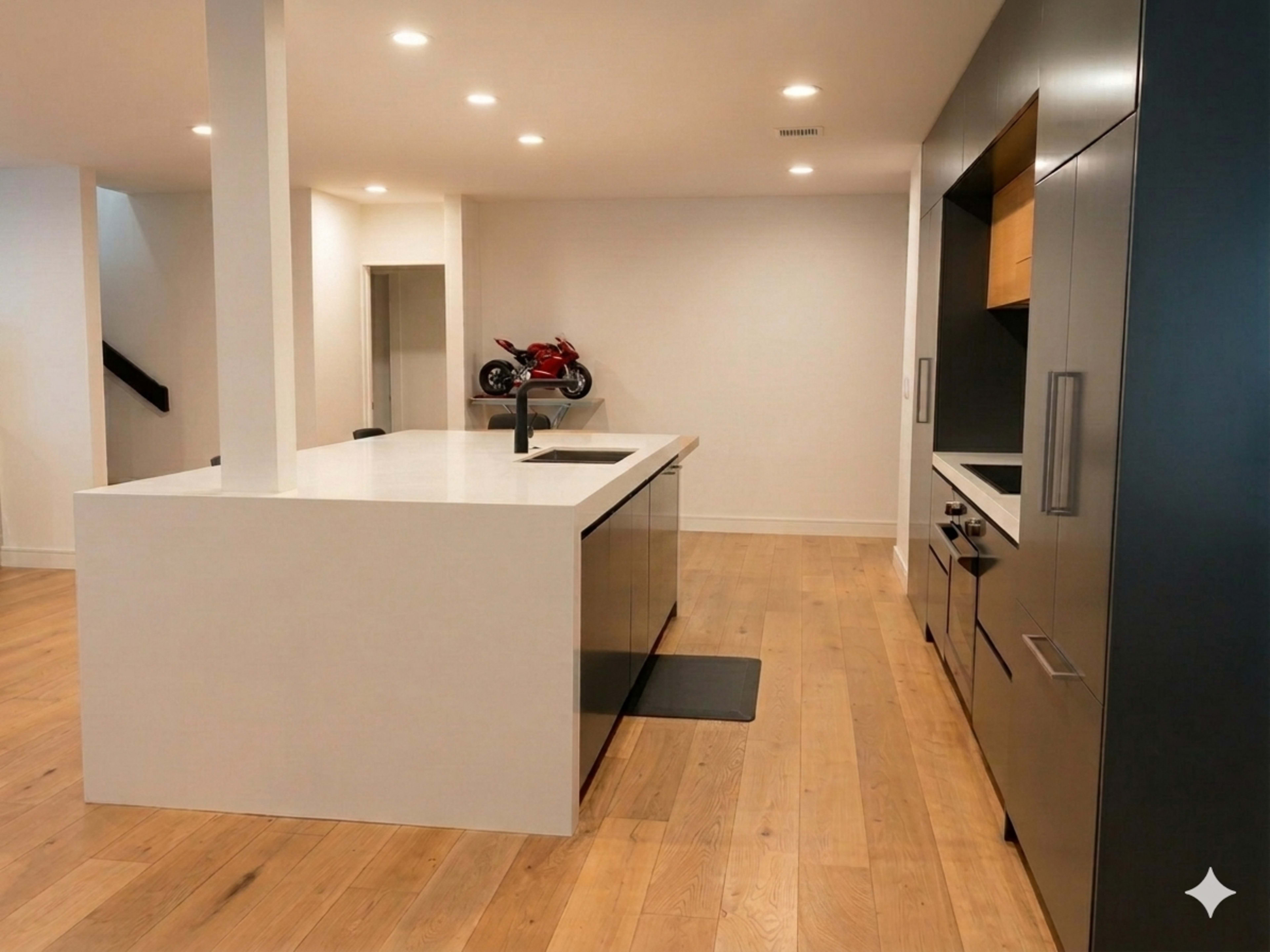 The image shows a modern kitchen with an island, stainless steel appliances, and a motorcycle displayed on a ledge in the background.