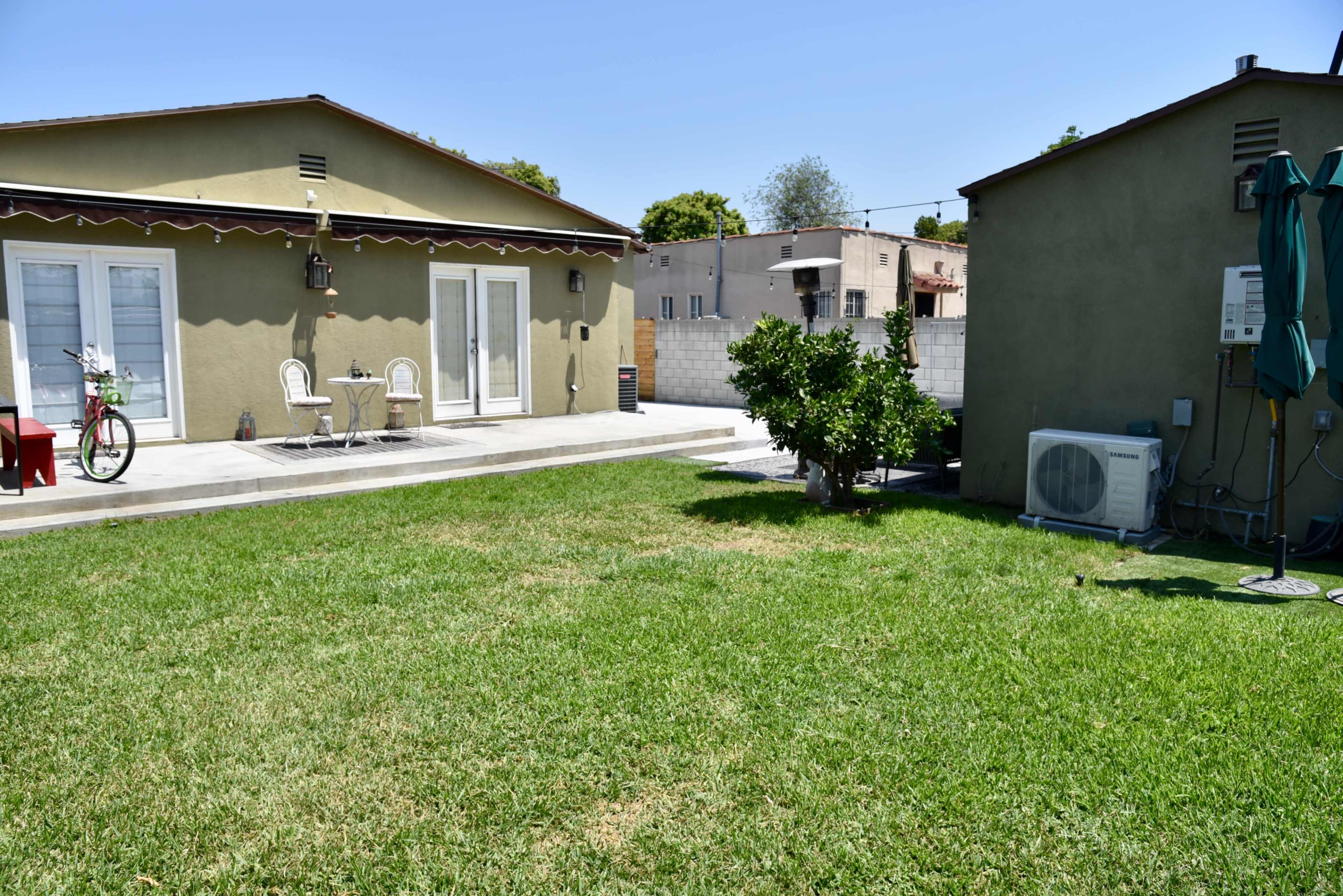 A well-maintained backyard with two small houses, lush green grass, and outdoor furniture.