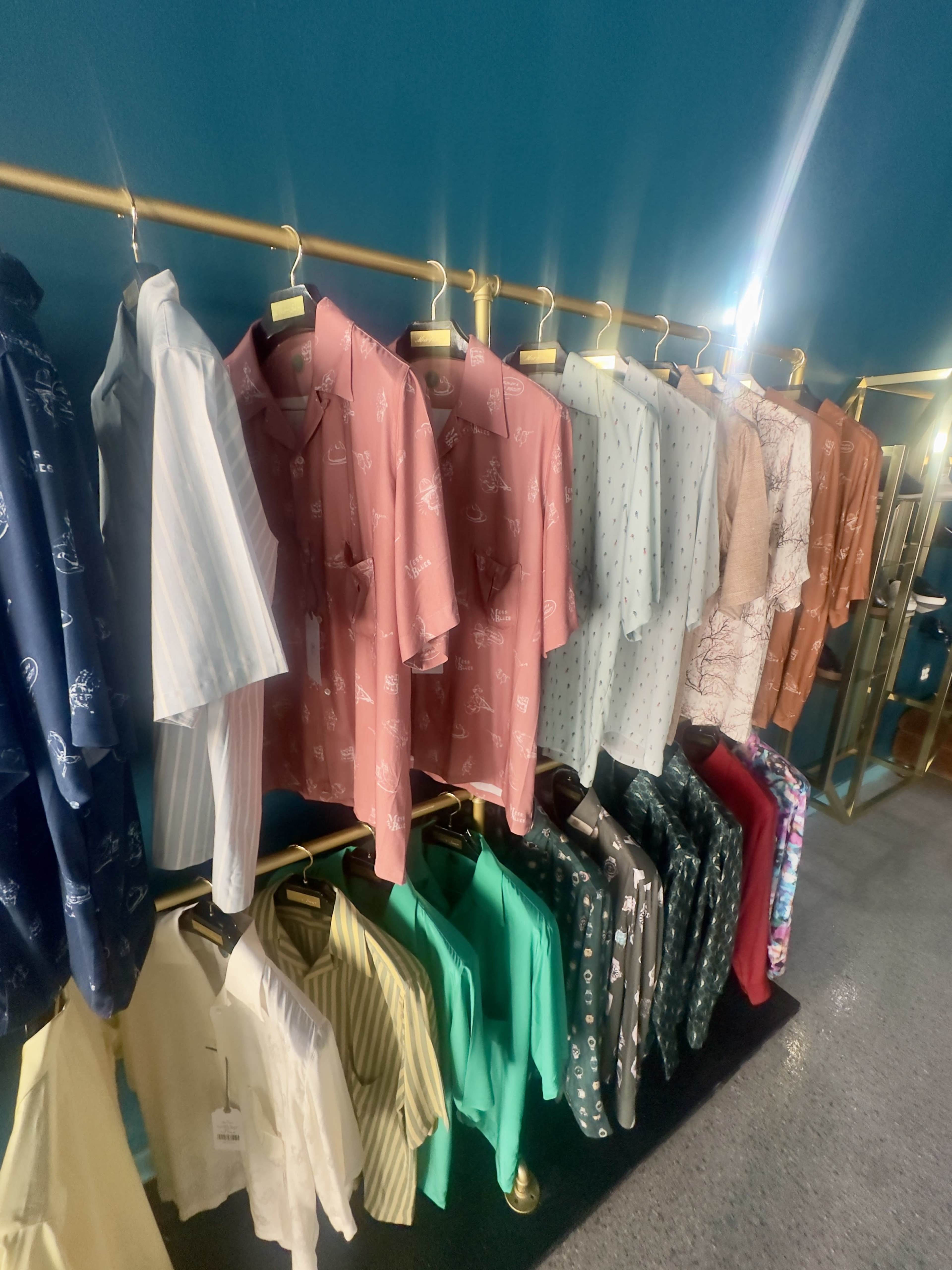 The image shows a row of colorful shirts hanging on a rack in a retail setting.