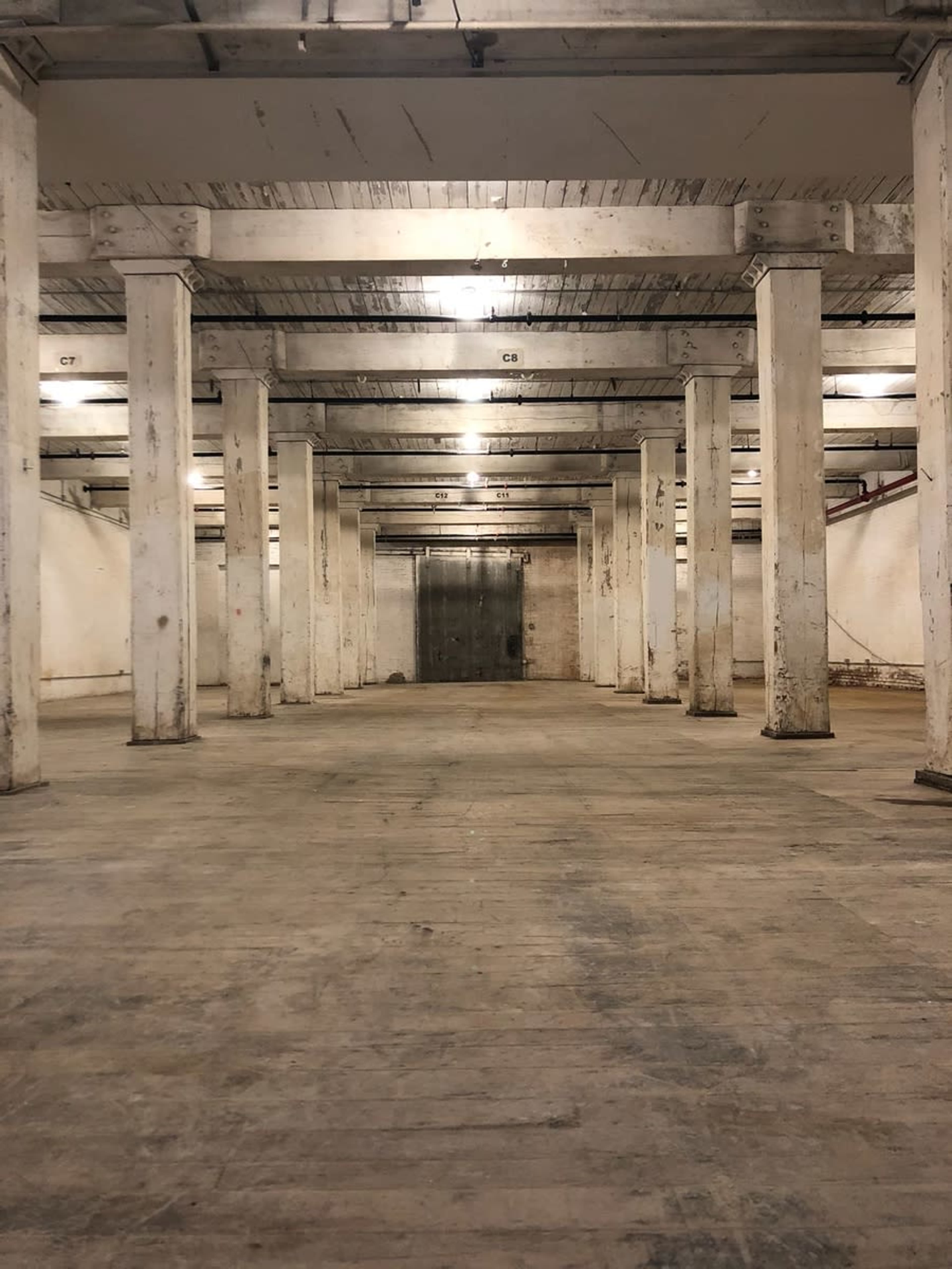 A large, empty industrial space with concrete pillars and dim overhead lighting.