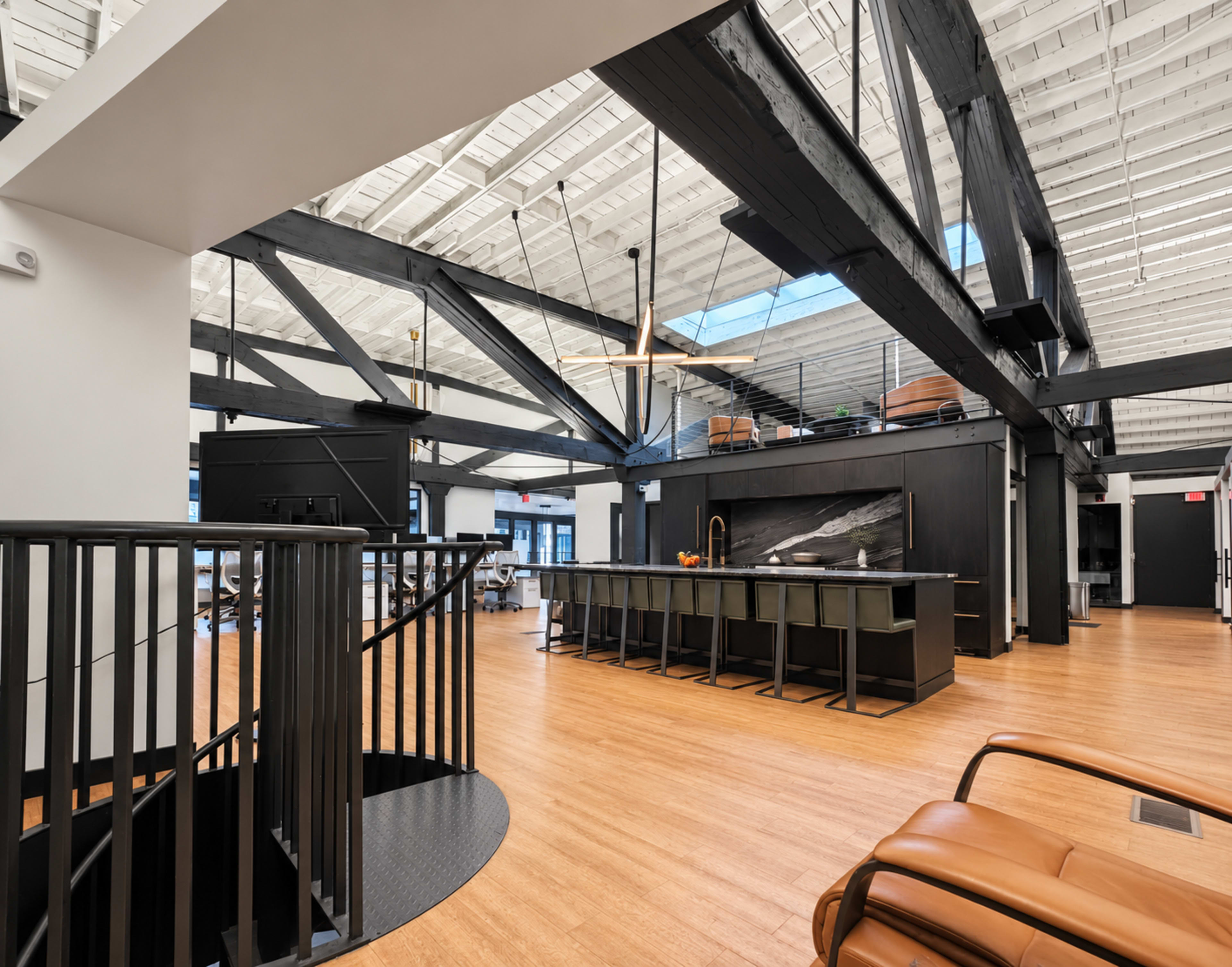 The image features a modern, open-concept interior space with high ceilings, wooden beams, and a kitchen island with seating.