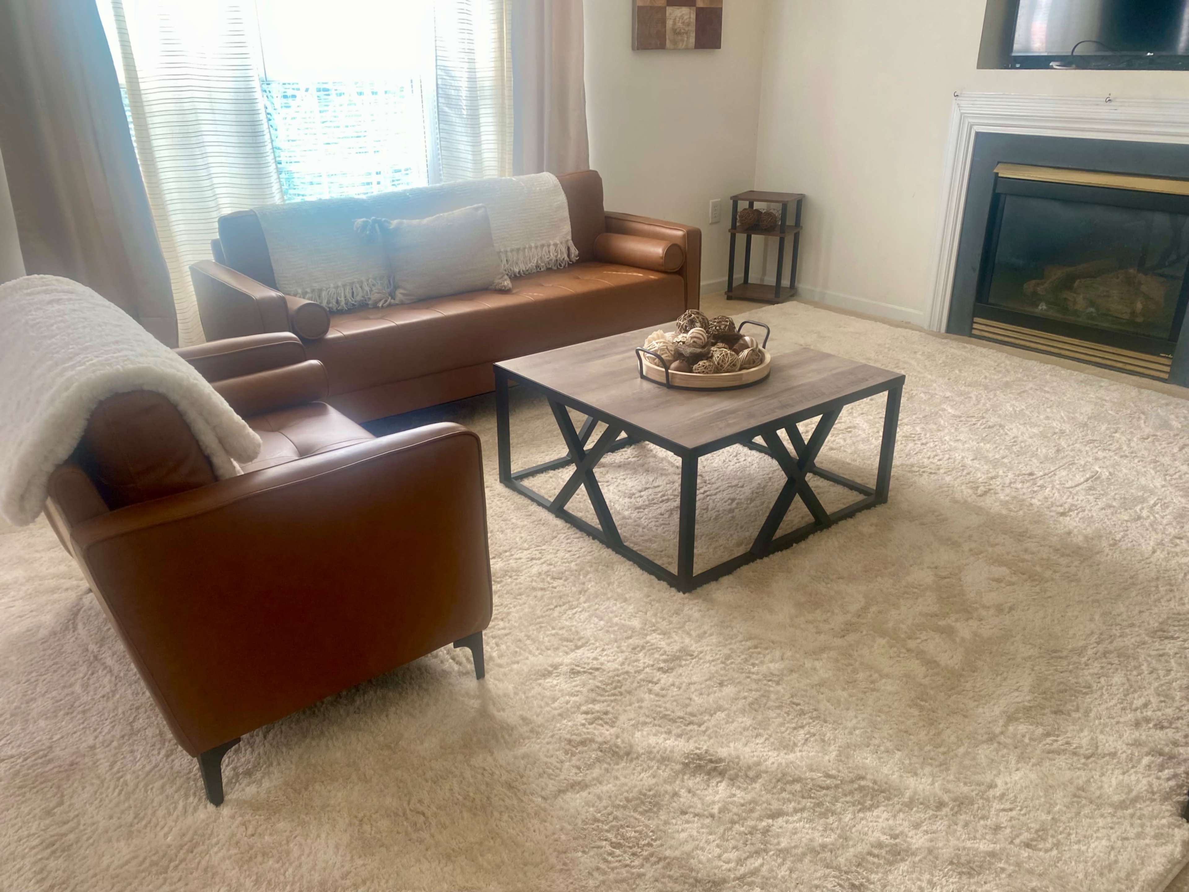 The image shows a living room featuring a leather sofa, a coffee table with decorative items, and a fireplace in the background.