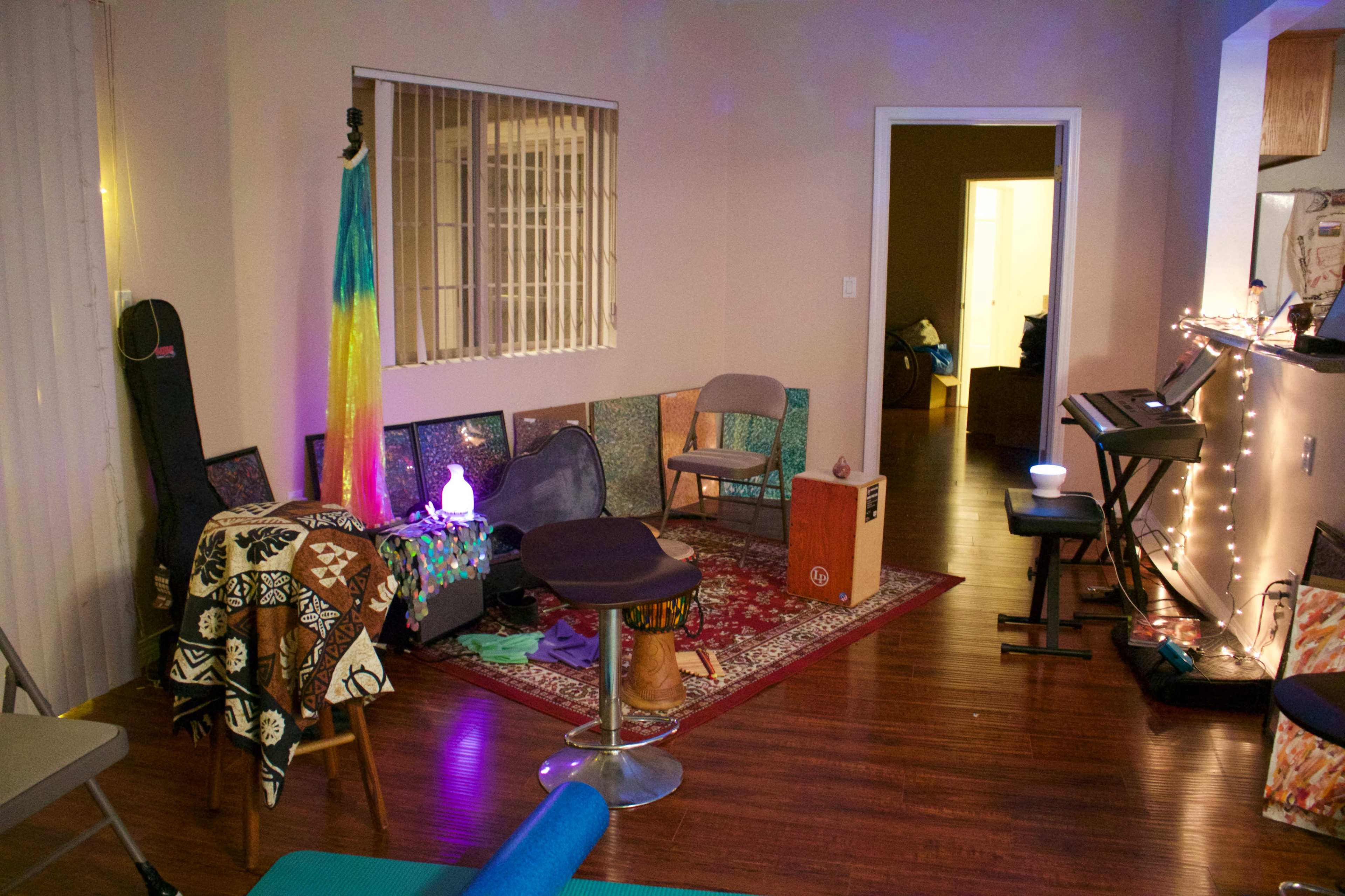 A cozy indoor space with a variety of seating, musical instruments, and colorful decor, including a lit corner and a patterned rug.