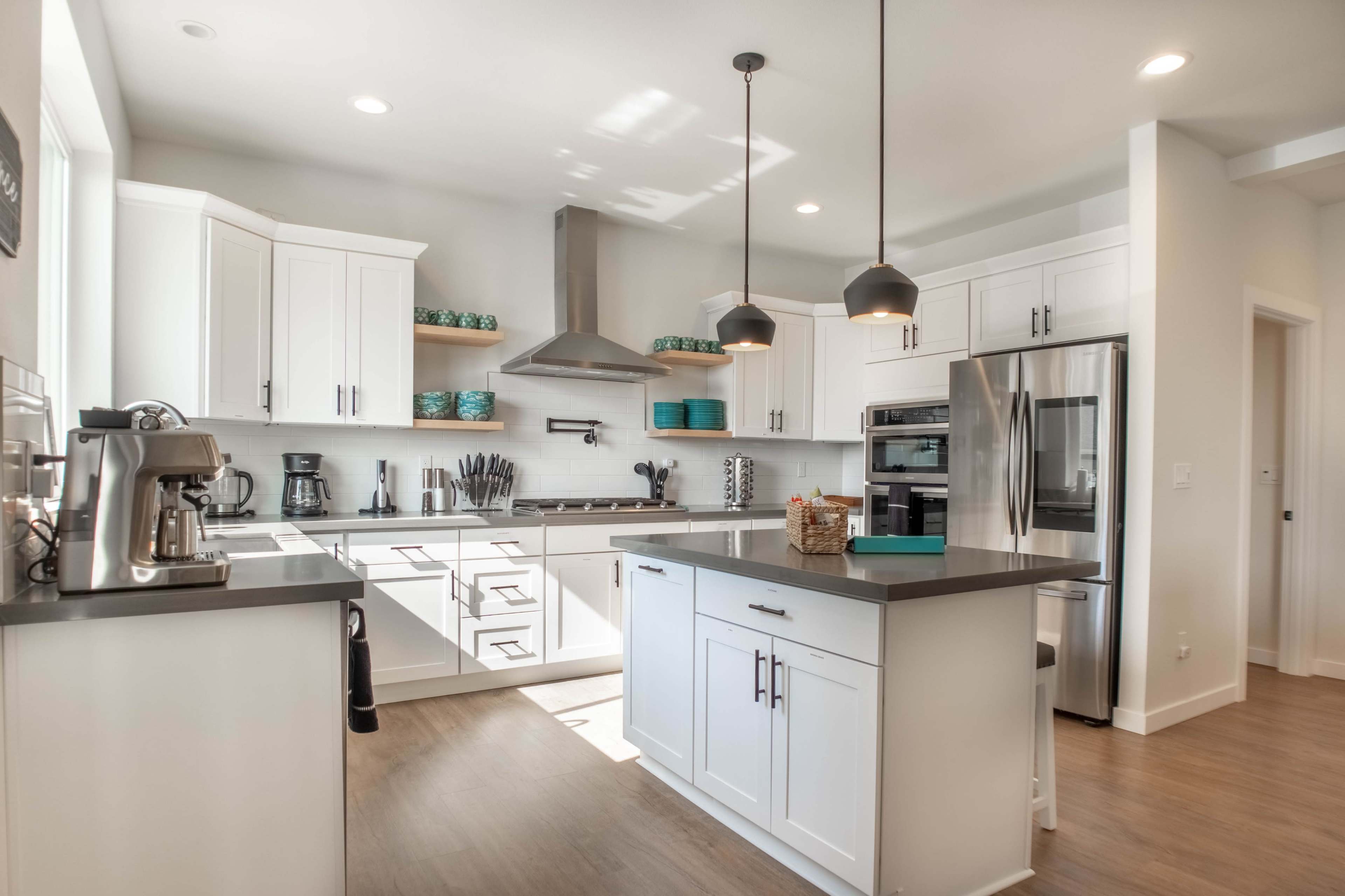 A modern kitchen features white cabinetry, stainless steel appliances, and a central island with a dark countertop.