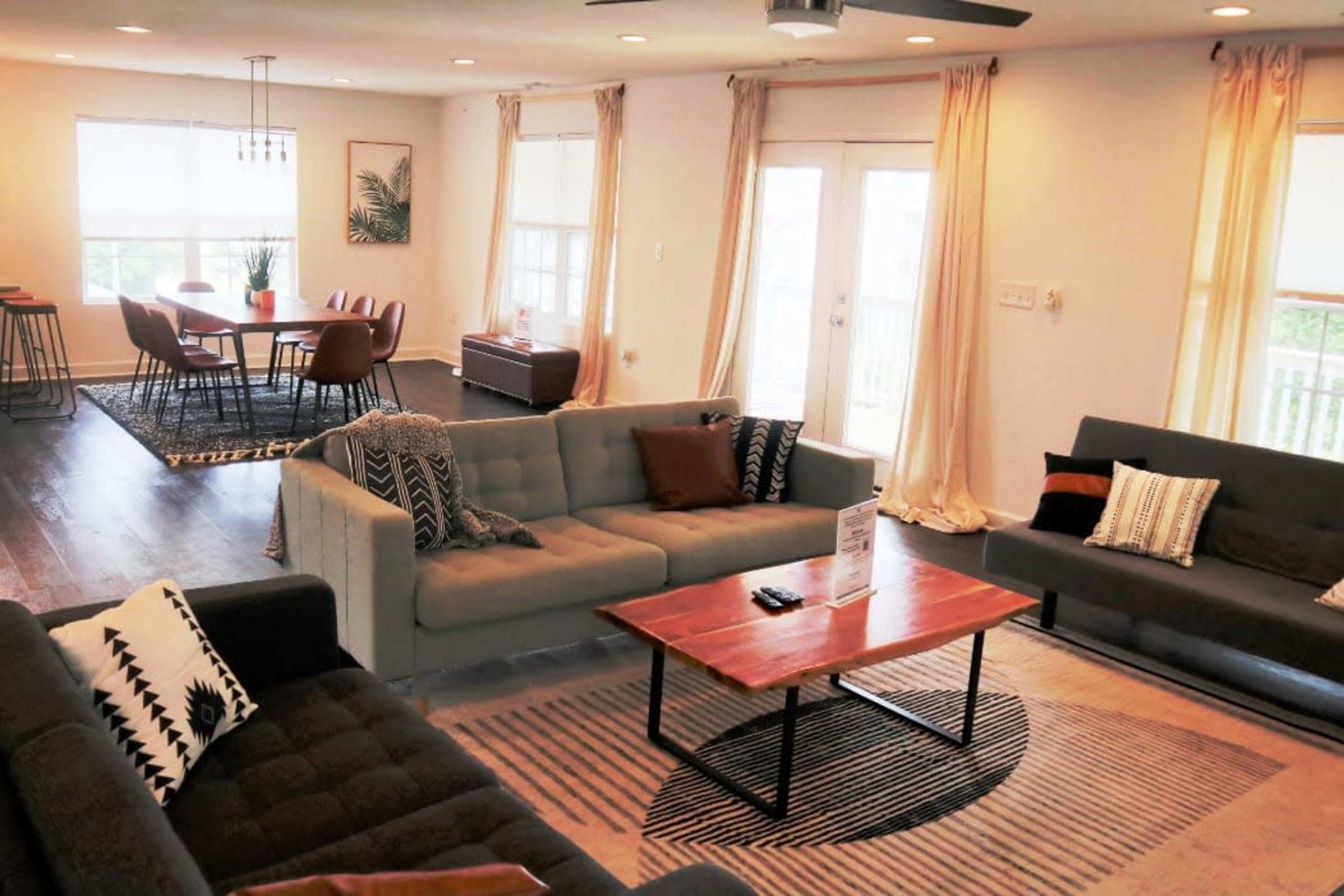 A spacious living area features two sofas facing a coffee table, with a dining table and chairs visible in the background.
