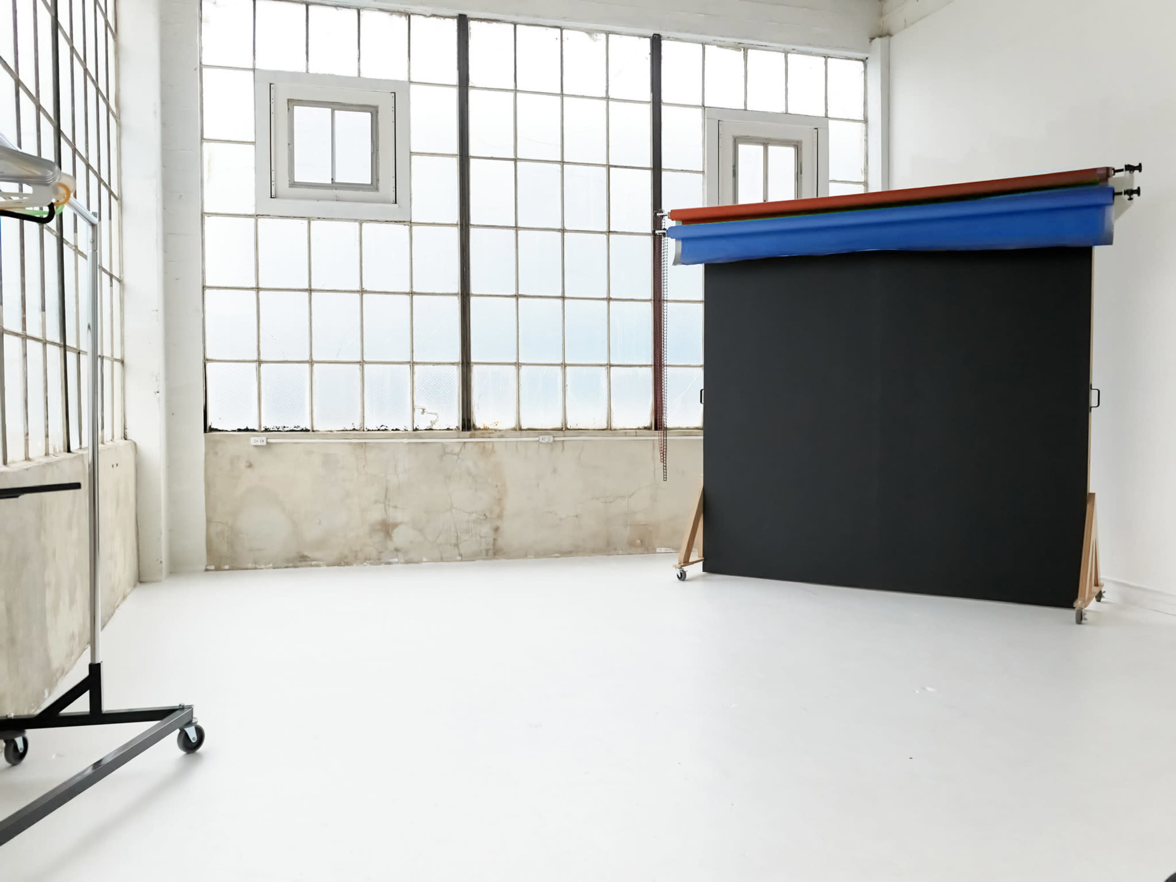 The image shows a spacious indoor studio with large windows and a black backdrop set against a plain white wall.