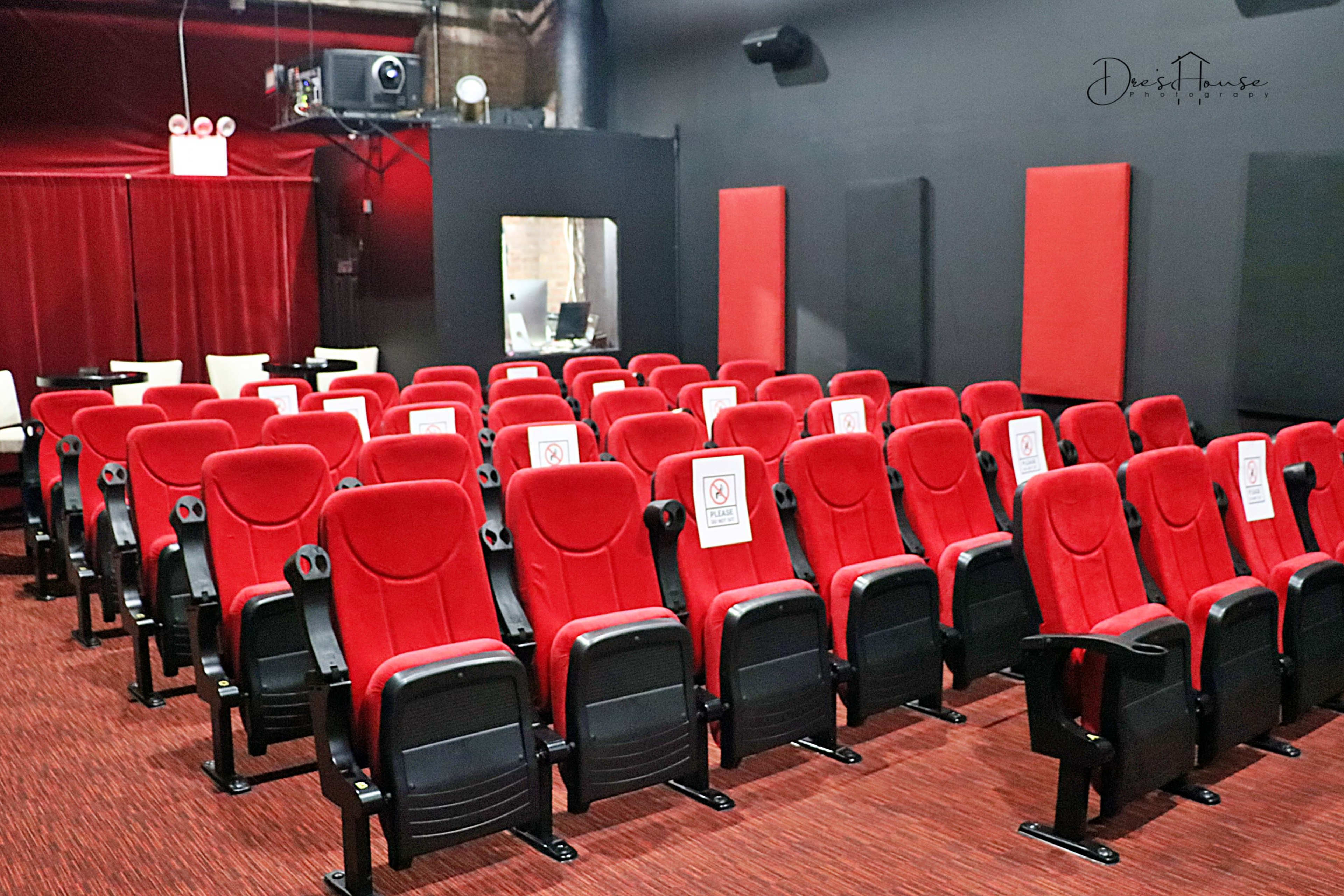 A row of red theater seats with signage indicating seating restrictions in a dimly lit cinema.