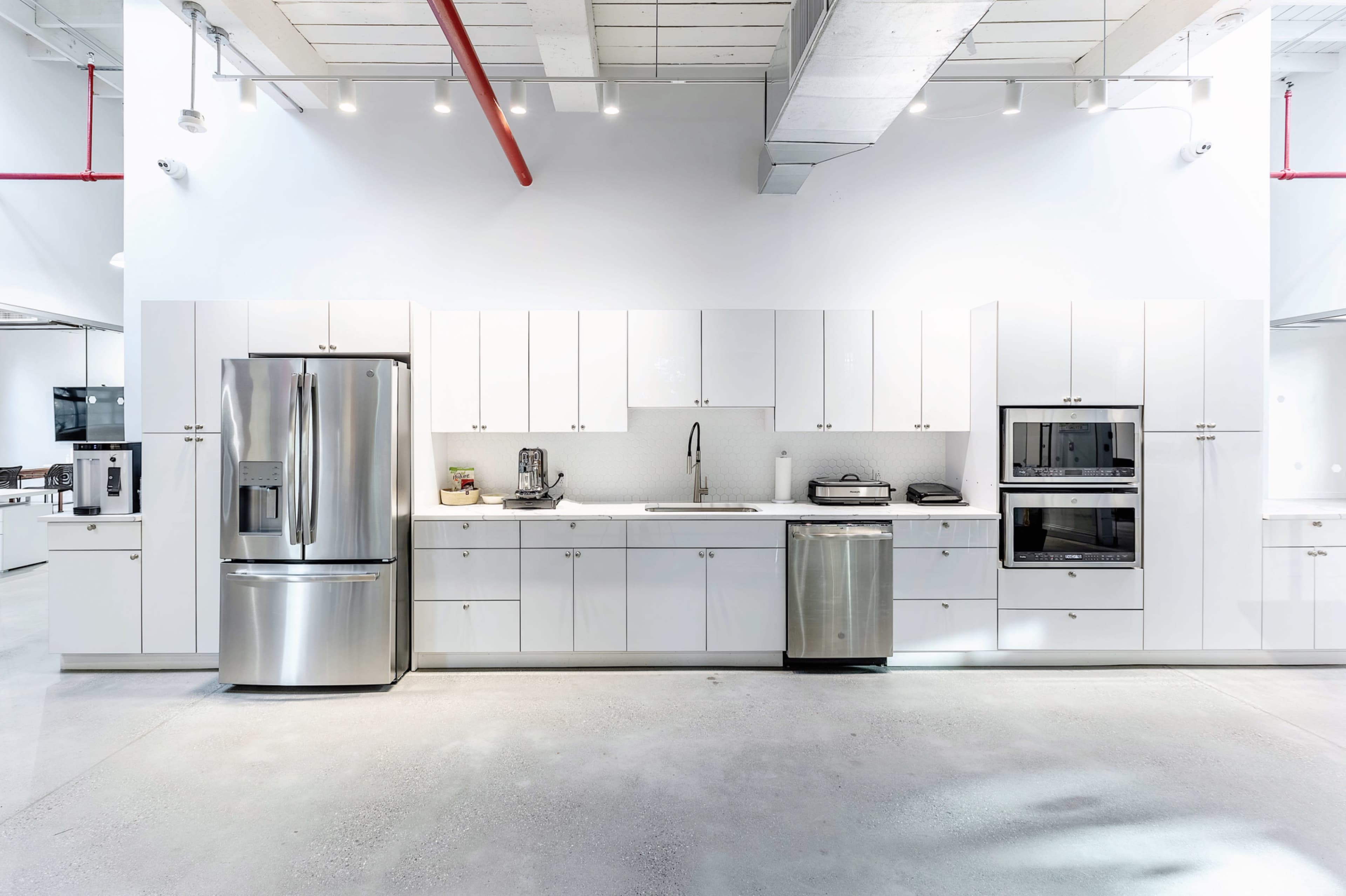 The image shows a modern kitchen with white cabinetry, stainless steel appliances, and a clean, minimalist design.