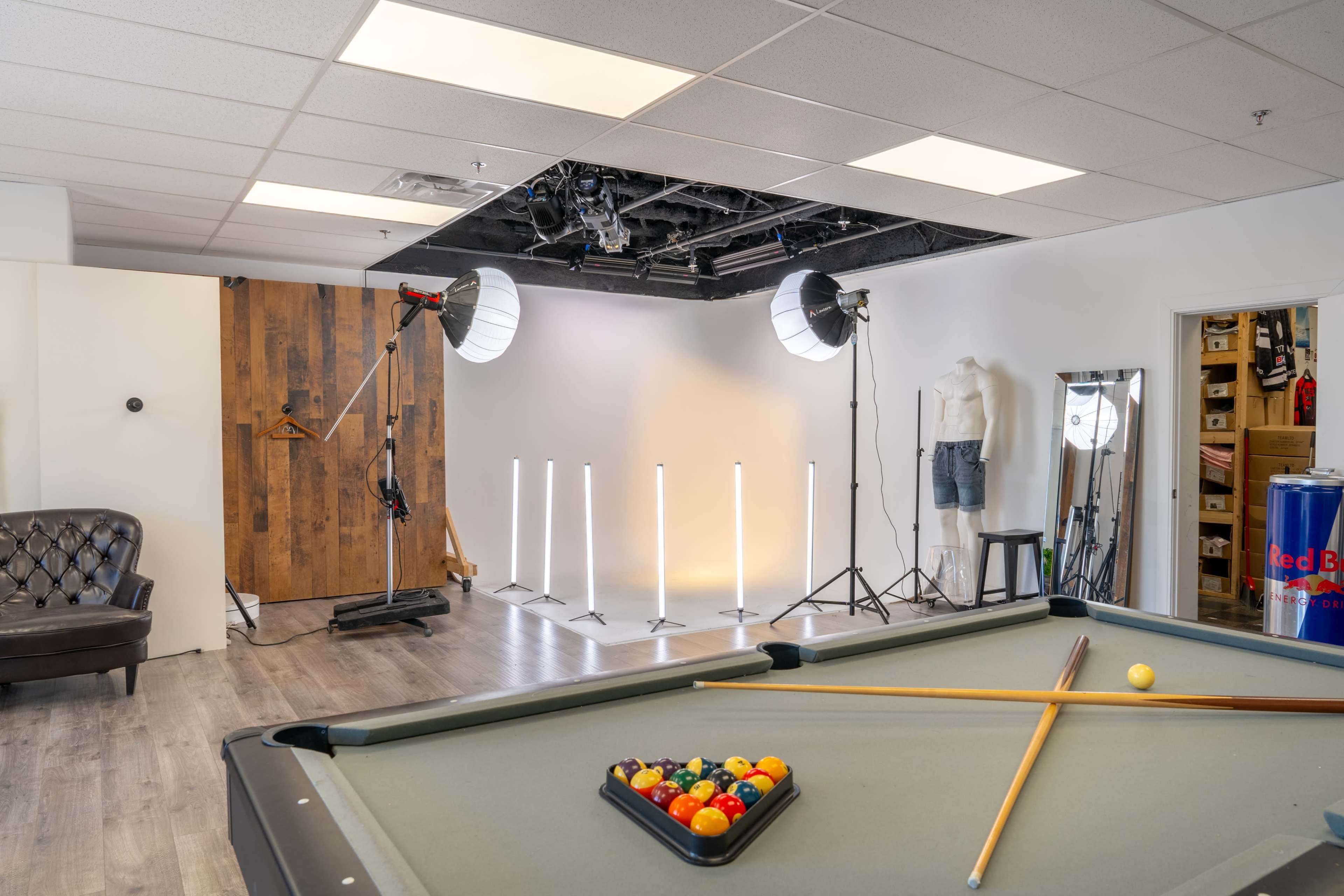 The image shows a spacious studio with a pool table in the foreground and photography lighting equipment set up in the background.