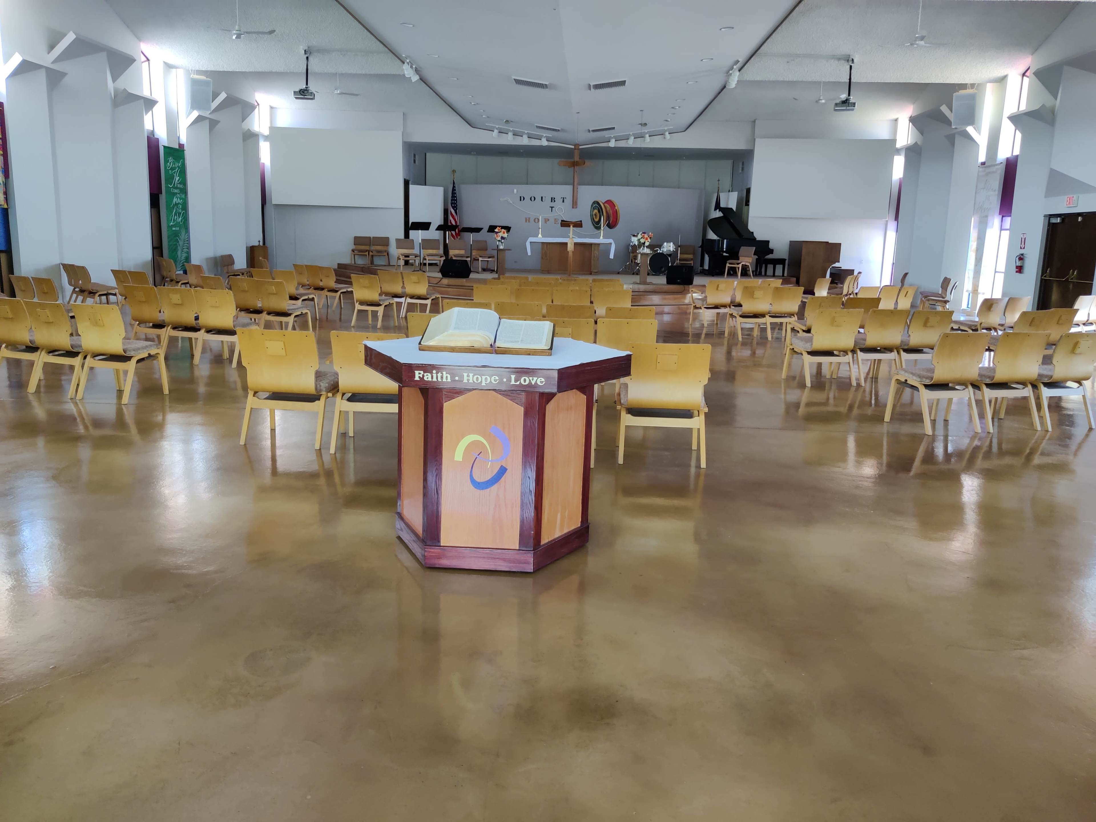 The interior of a church features a central altar surrounded by rows of wooden chairs and various religious symbols.