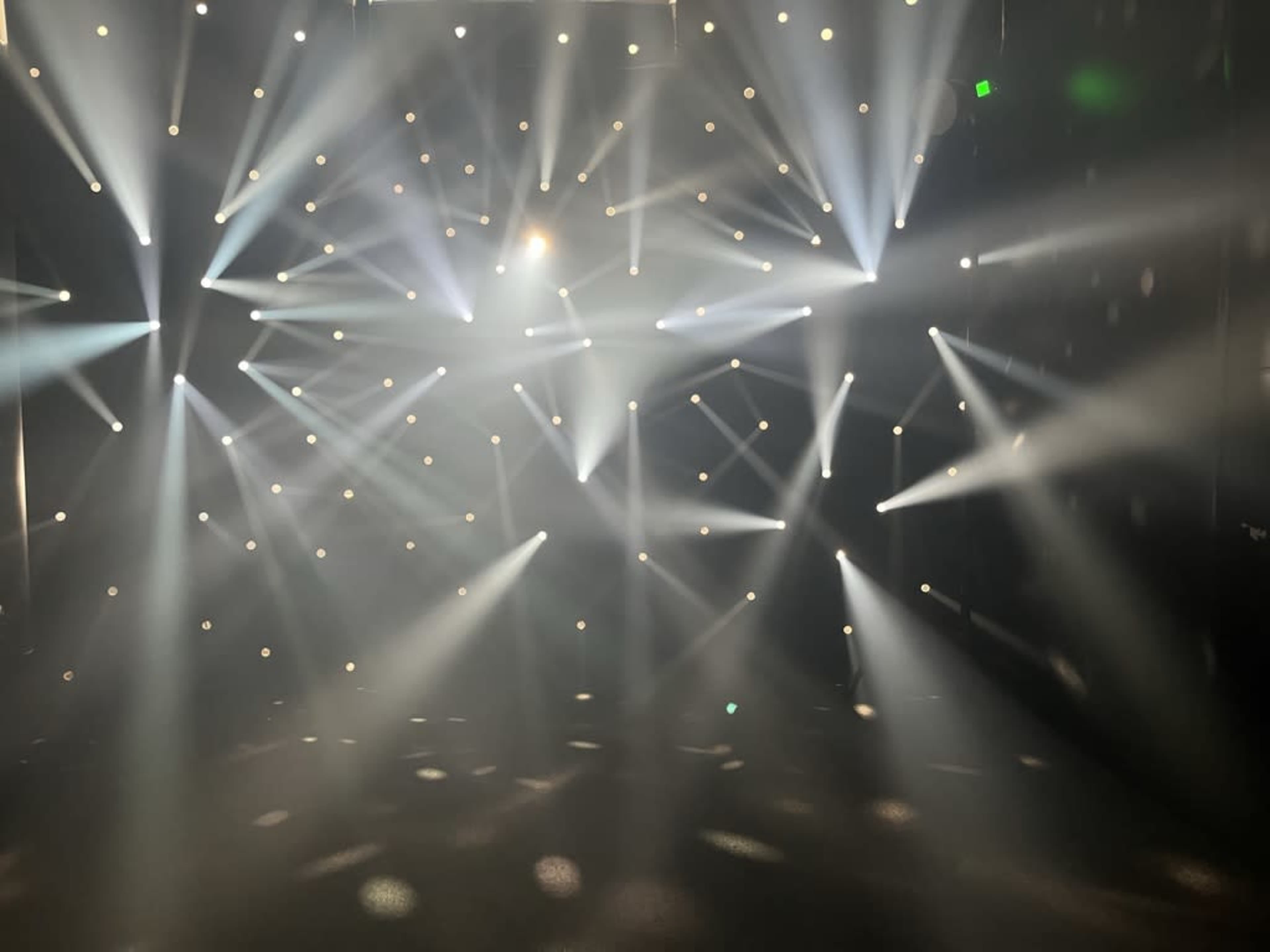 The image shows a stage illuminated by multiple beams of light shining through fog.
