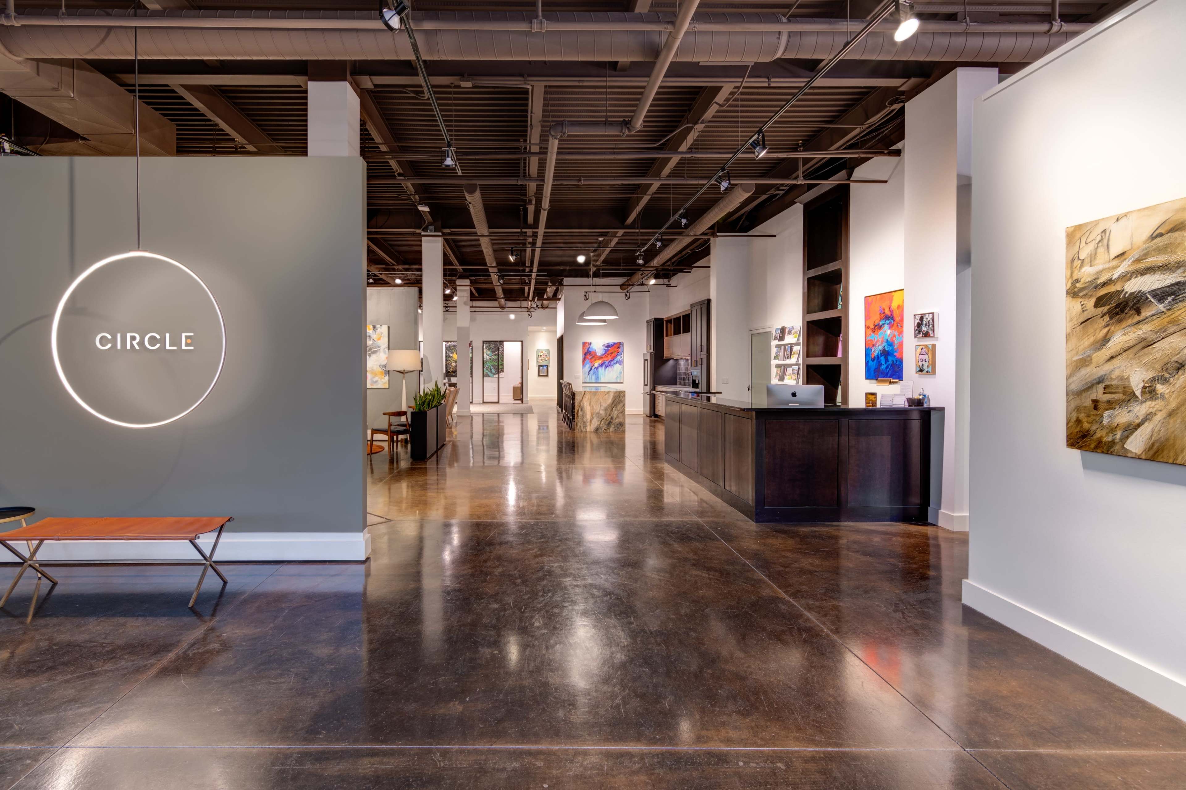 A modern art gallery with a reception area, illuminated sign reading "CIRCLE," and artworks displayed on the walls.