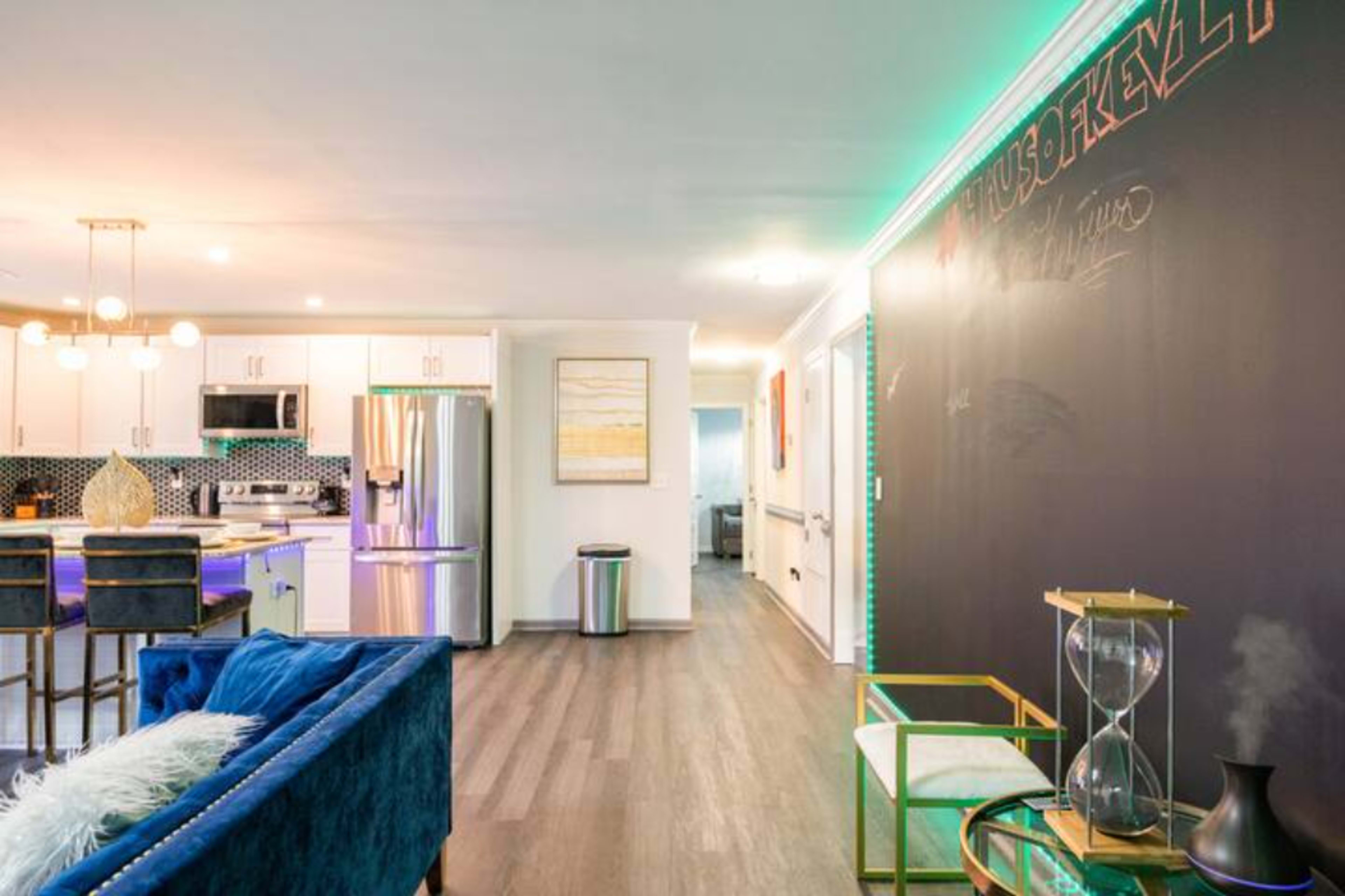 A modern open-concept living space featuring a kitchen, a dining area with bar seating, and a black chalkboard wall.