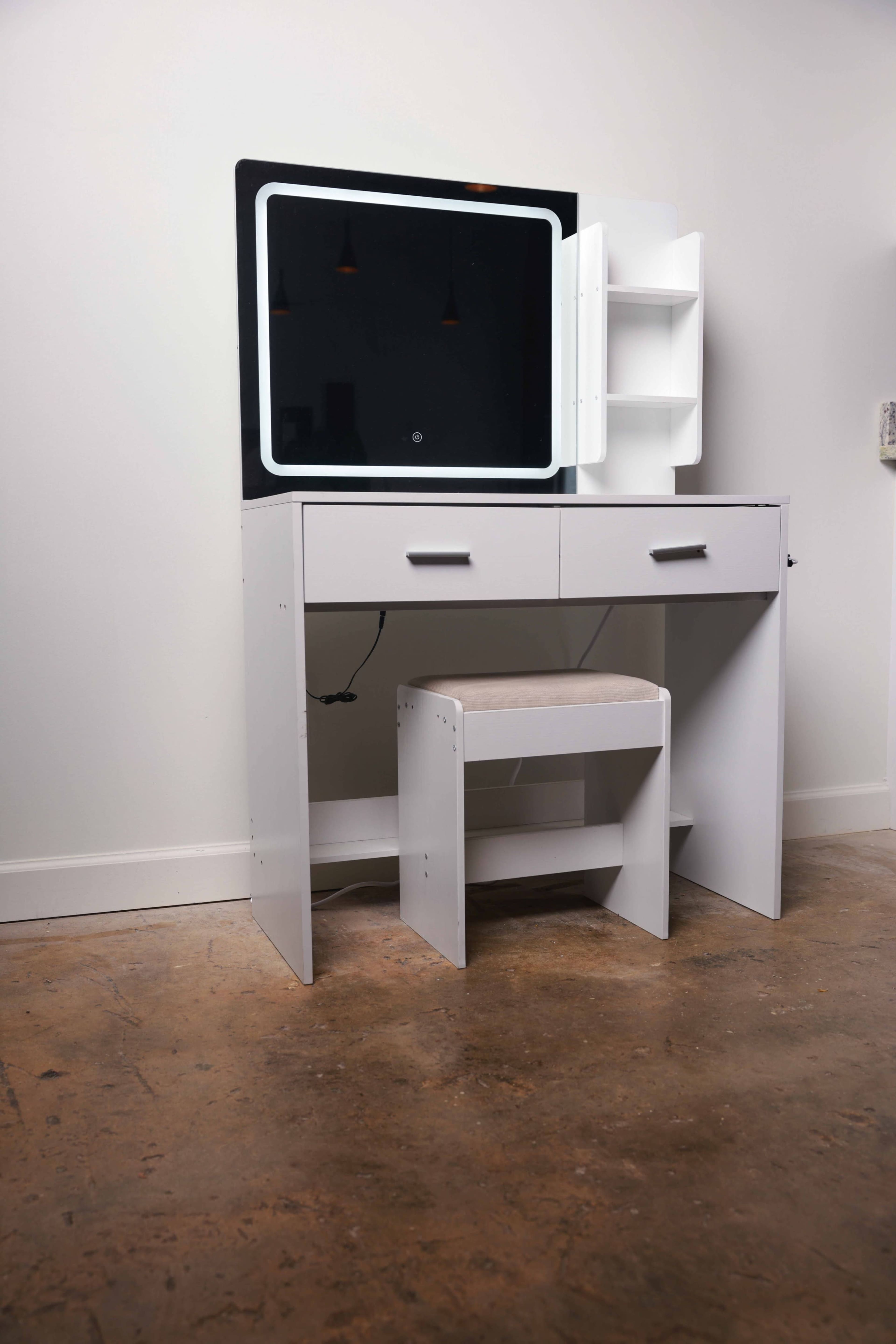 The image shows a minimalist white desk with a built-in mirror mounted above and a small stool tucked underneath.