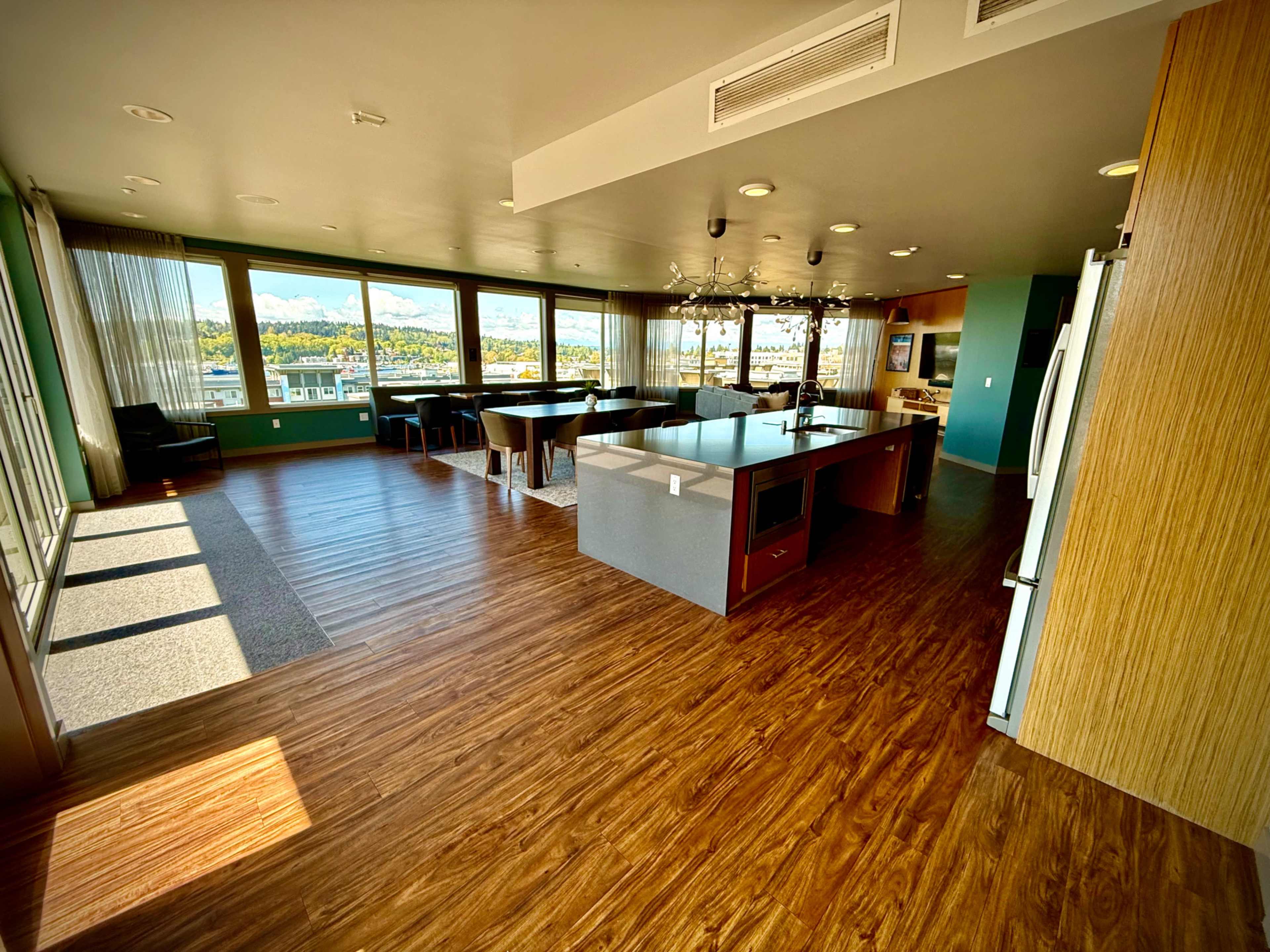 The image shows a spacious modern kitchen and dining area with large windows offering a view of mountains.