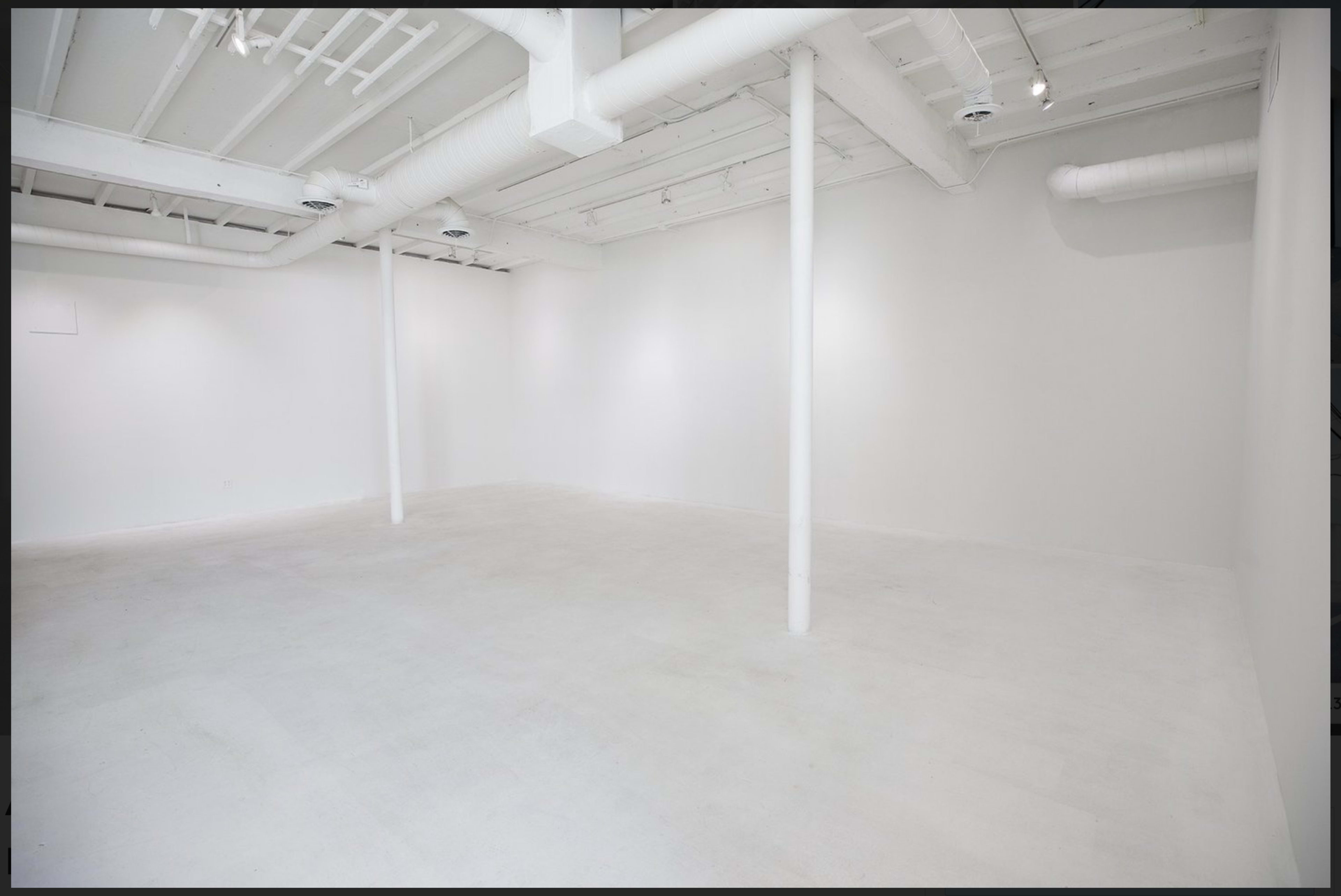 The image shows a spacious, empty room with white walls, a white ceiling, and several columns.