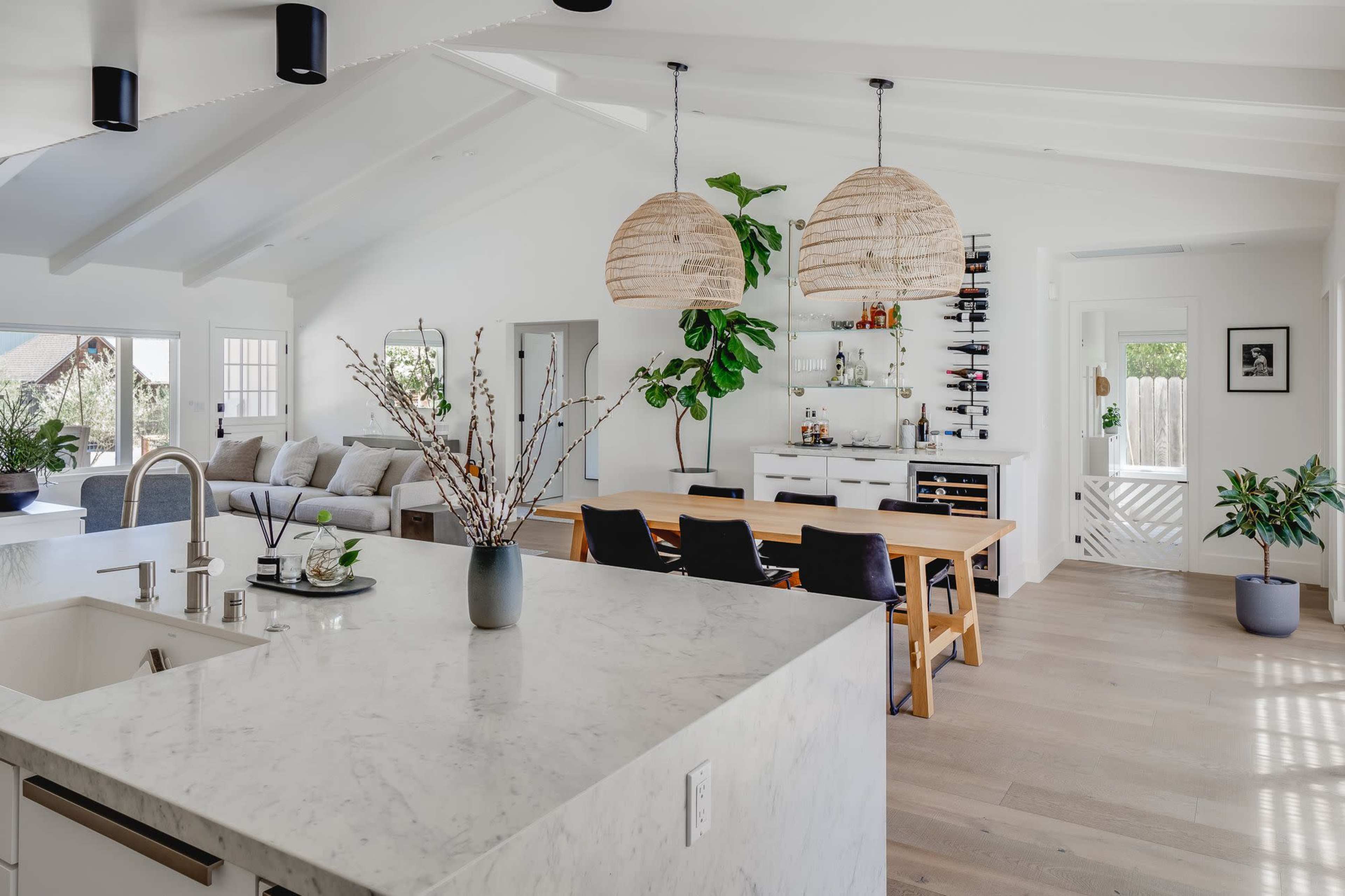 A modern open-concept living space featuring a kitchen with a marble countertop, a dining area with a wooden table, and a comfortable seating area.