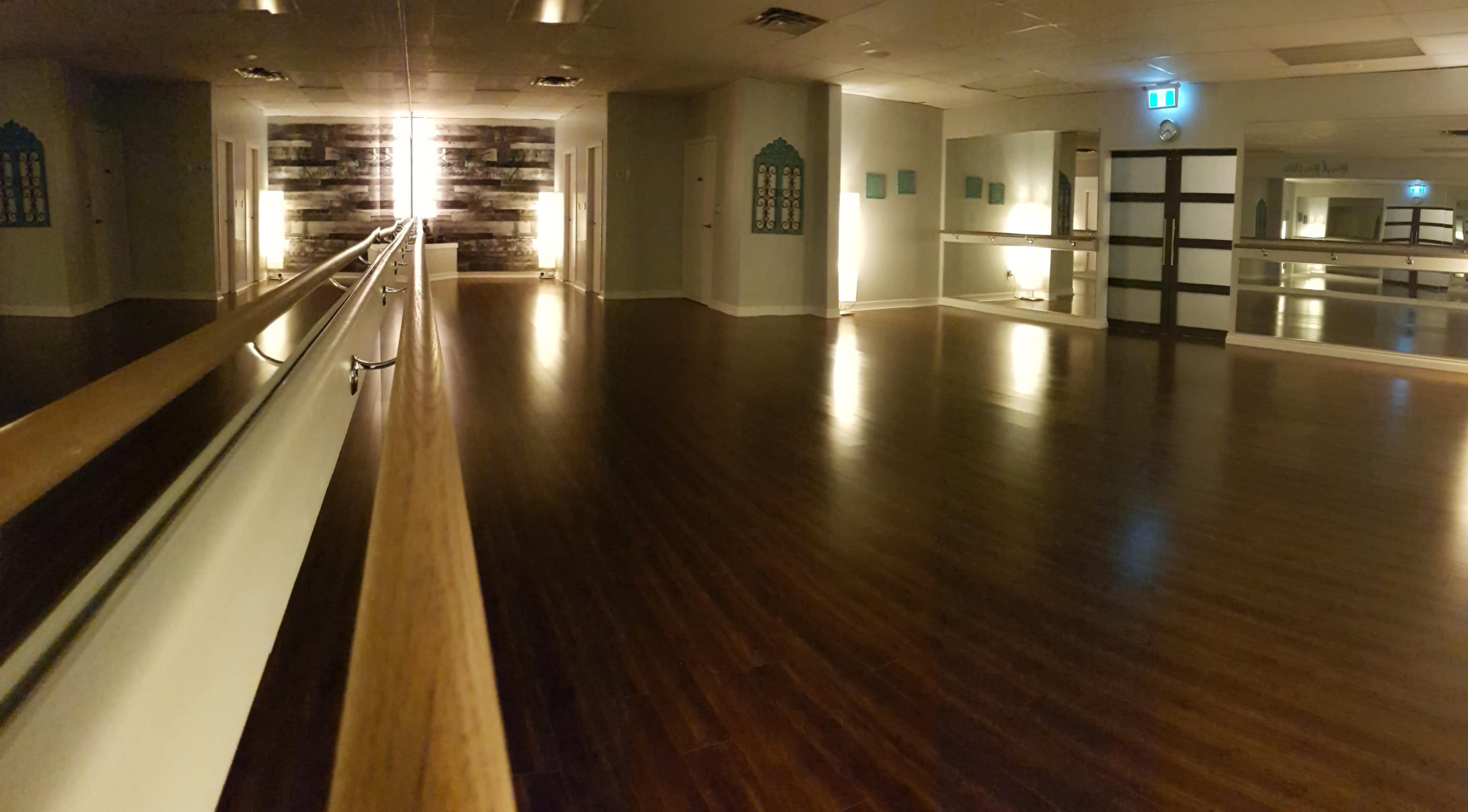 A polished dance studio features a wooden floor, mirrored walls, and ambient lighting.