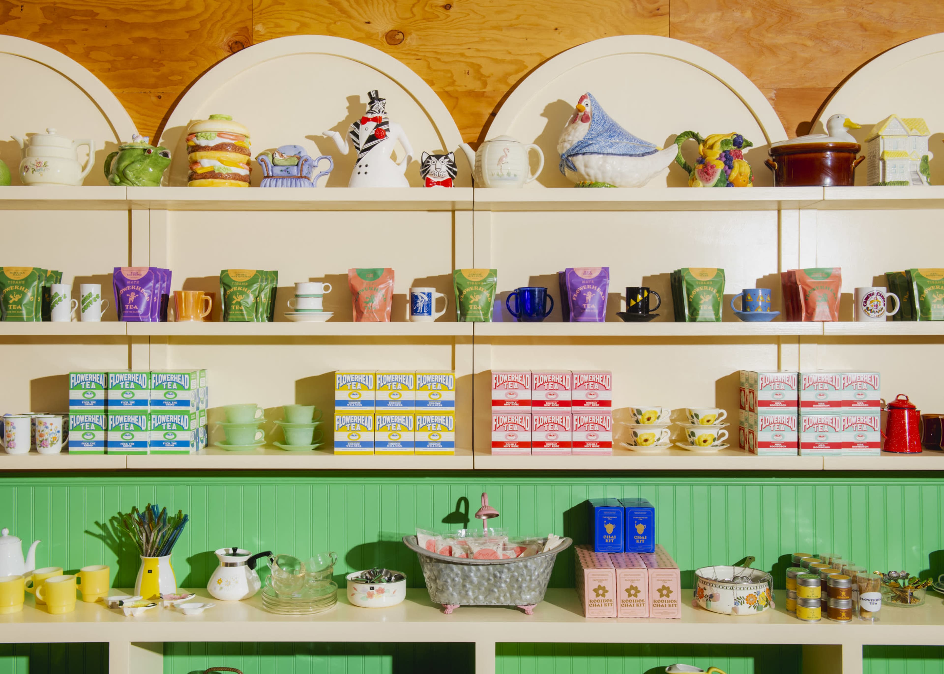 A colorful display of vintage ceramics and tea sets is arranged neatly on shelves in a quaint shop.