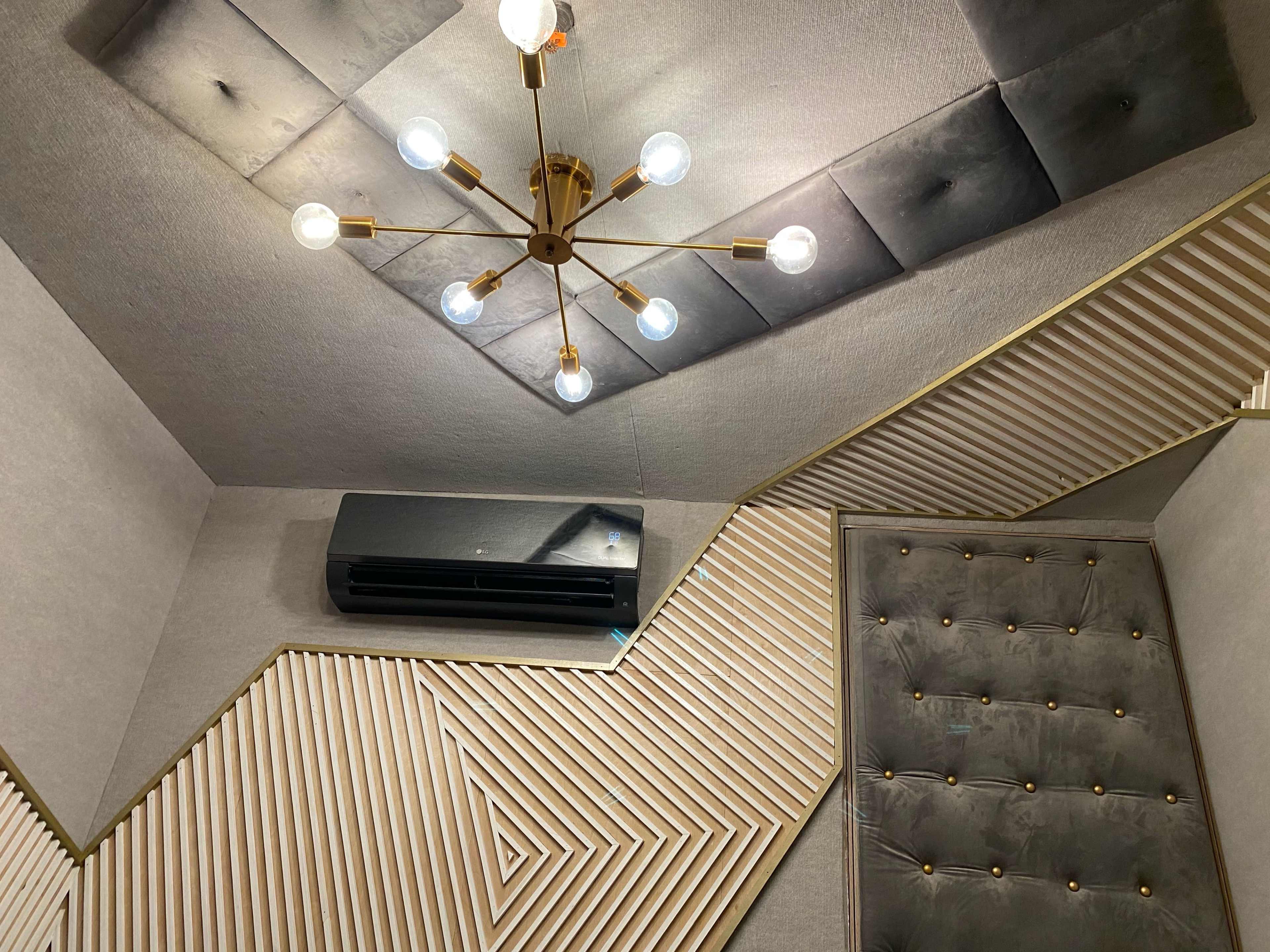 A modern interior design featuring a ceiling light fixture, geometric wall panels, and an air conditioning unit.