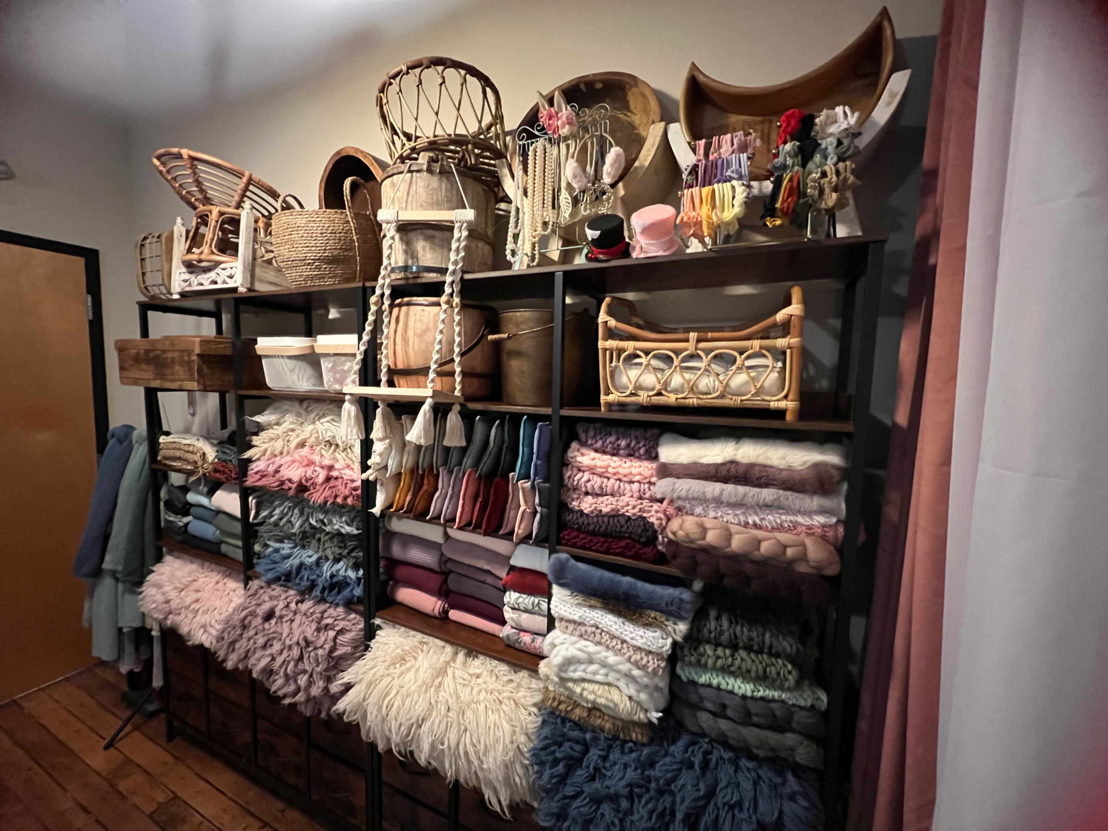 The image shows a shelving unit filled with various colorful blankets and throws, neatly arranged alongside baskets and decorative items.