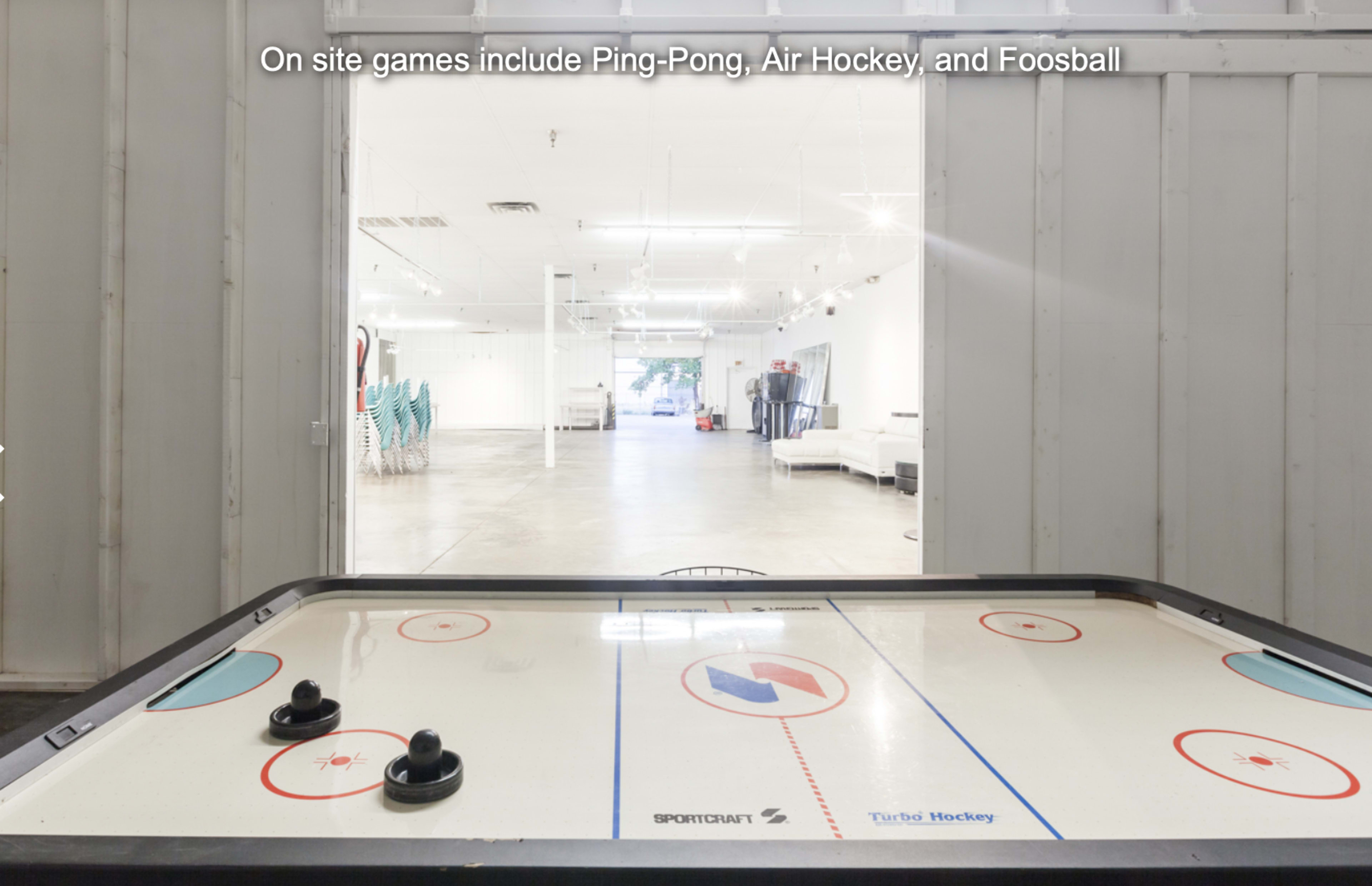 An air hockey table in a bright, spacious room with seating in the background.