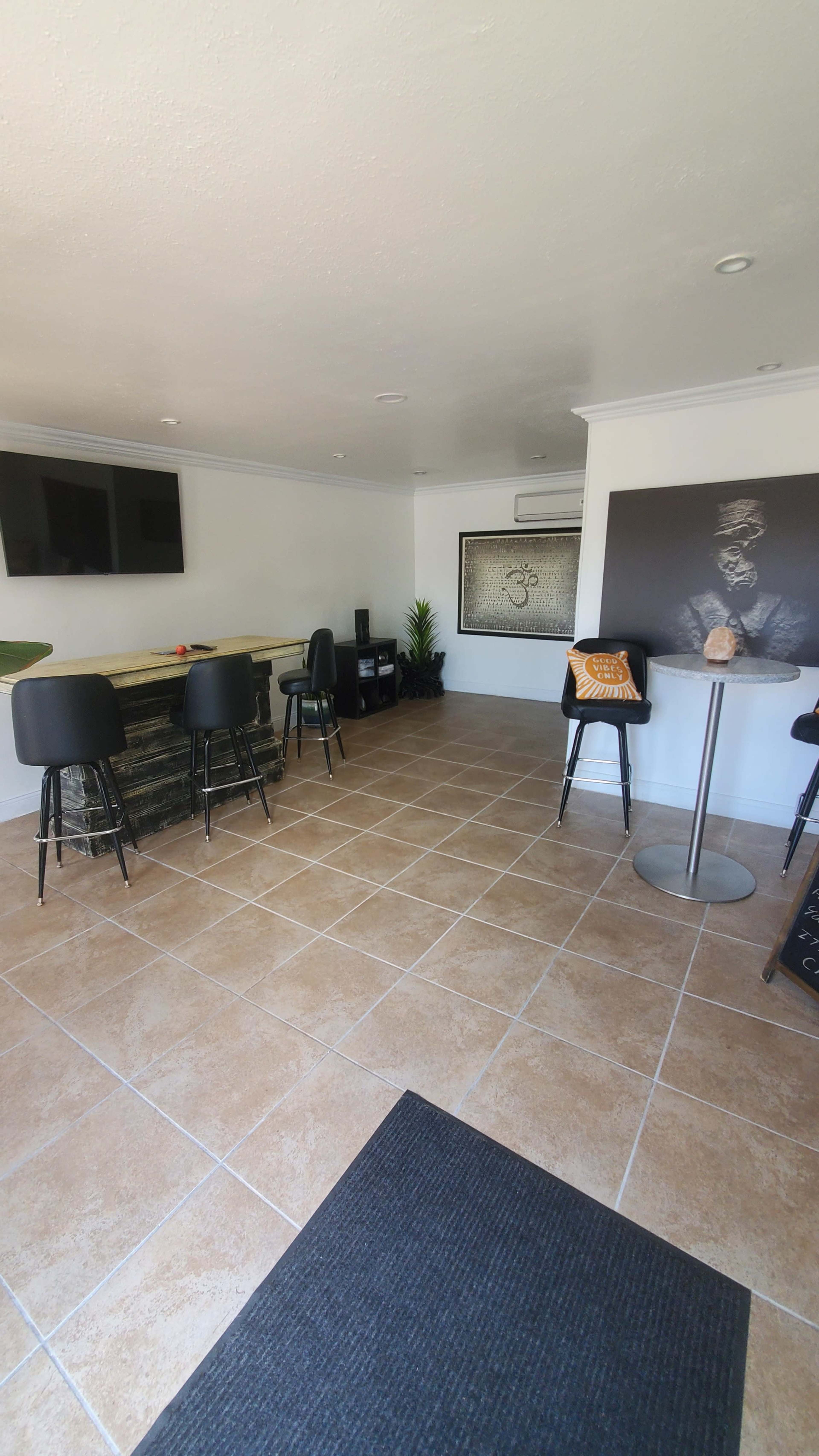 A spacious interior with tiled flooring, featuring a bar area with stools, a seating area, and decorative wall art.