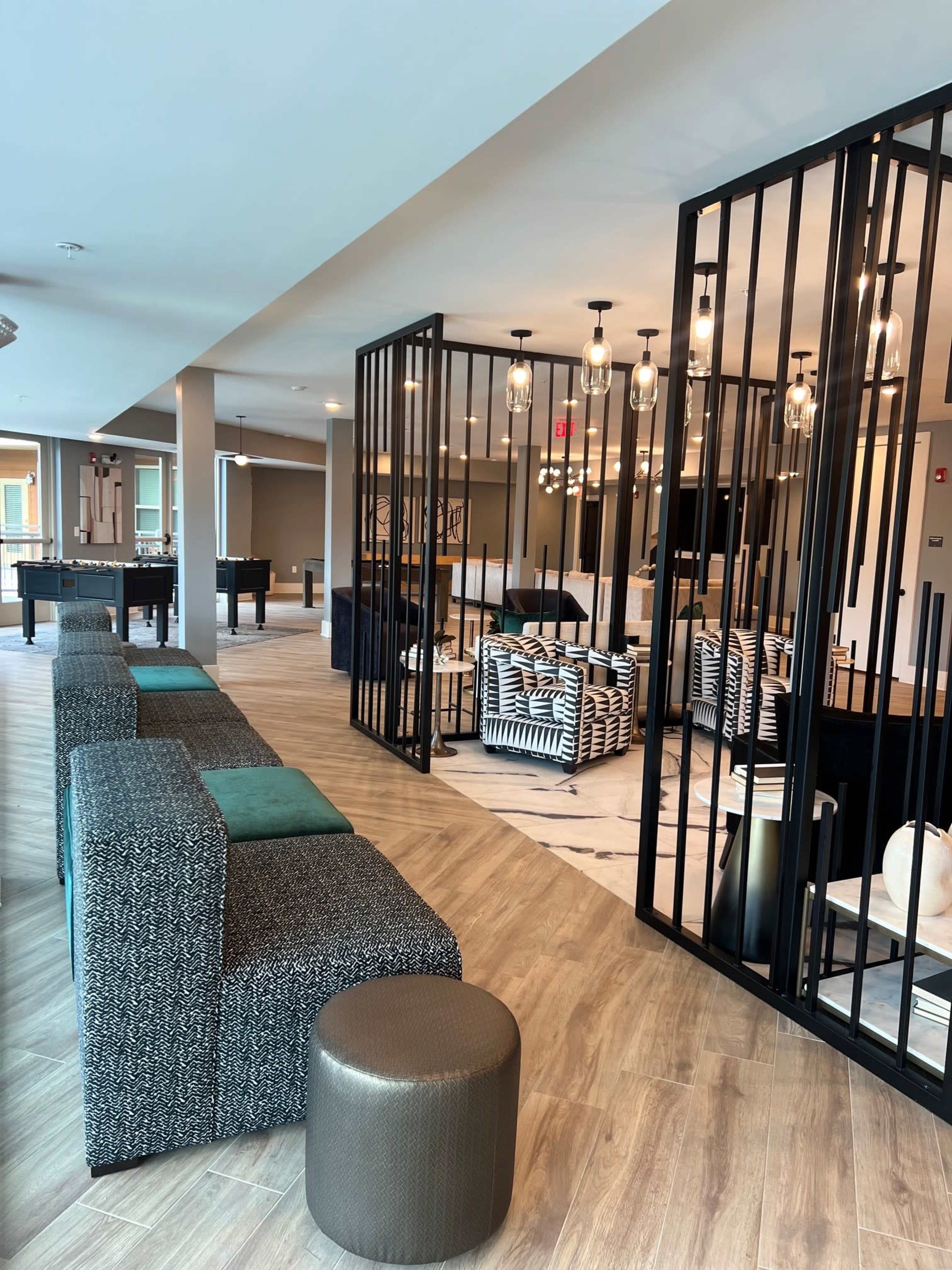 The image shows a modern lounge area with patterned seating and partitions, featuring a mix of tables and lighting fixtures.