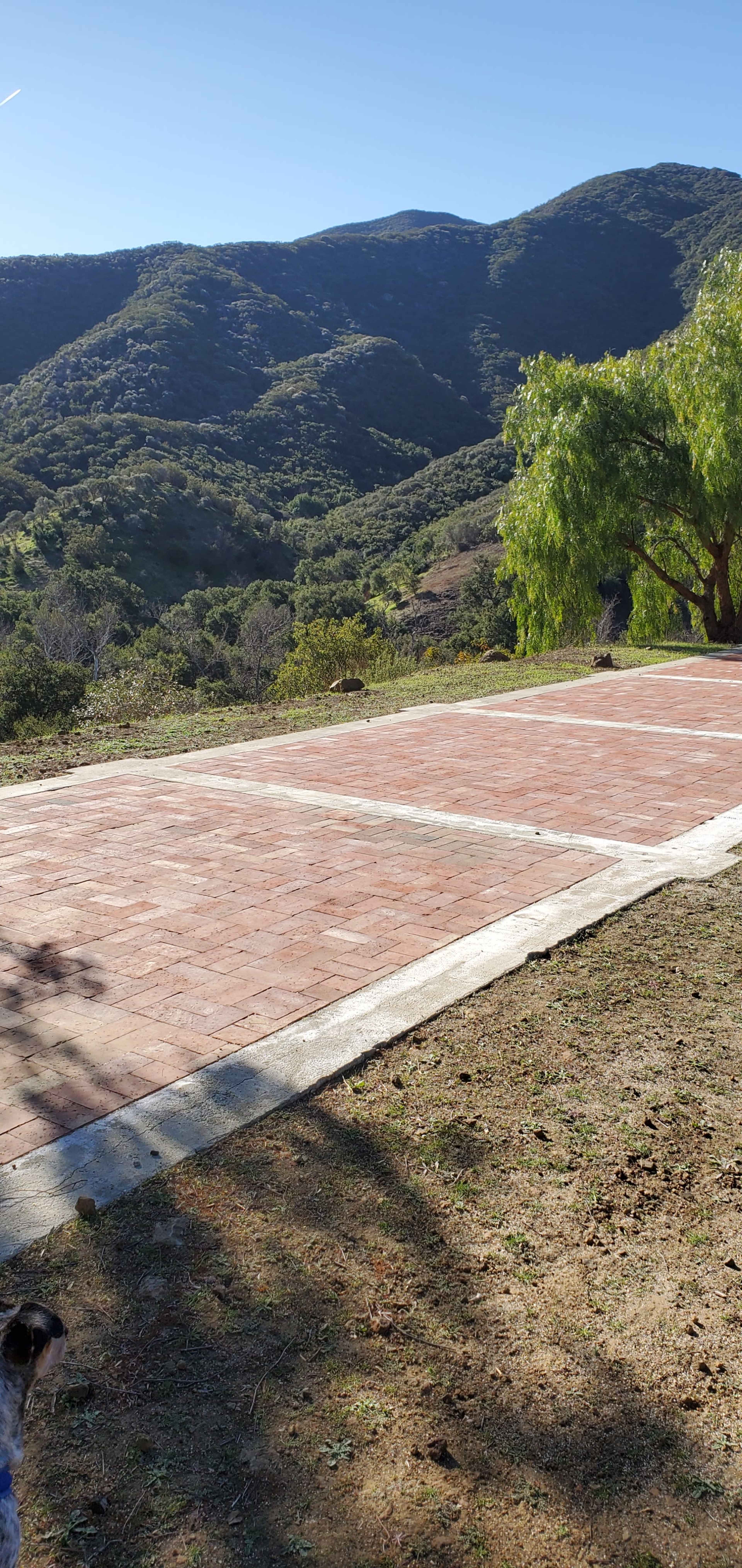 A paved area surrounded by hills and trees under a clear sky.