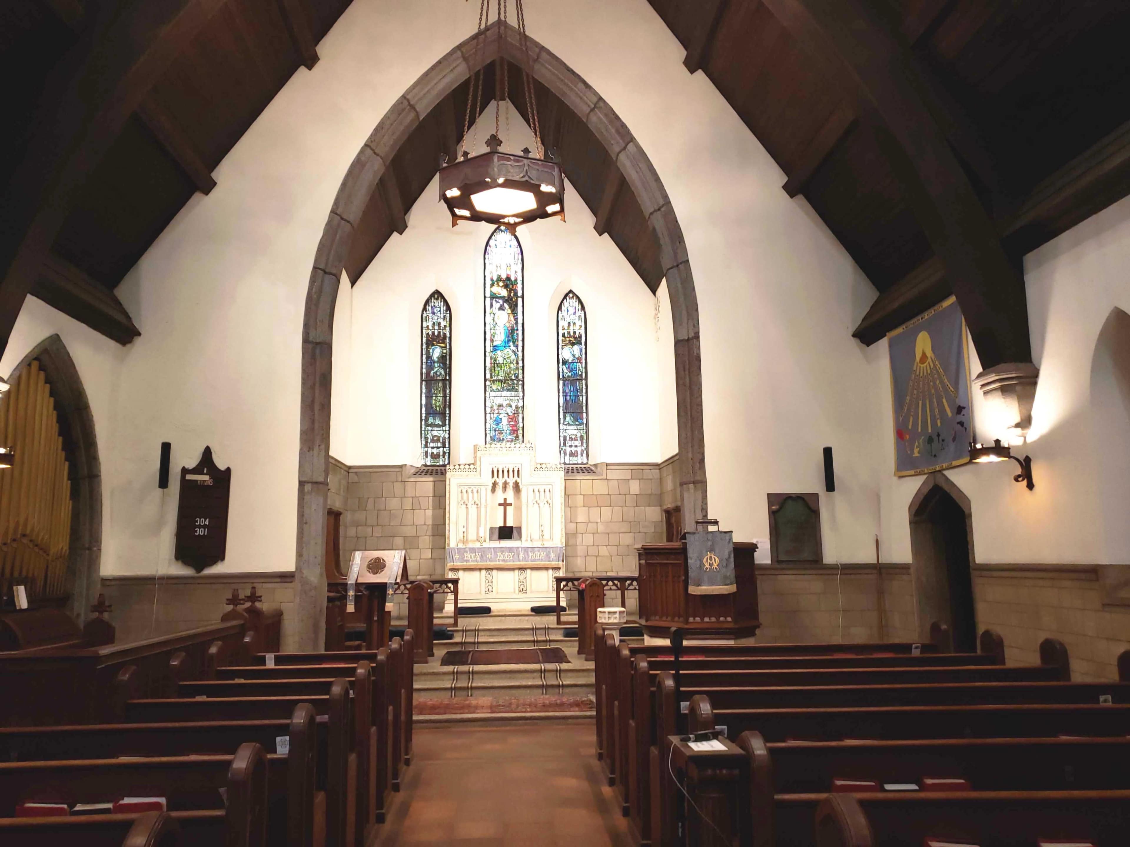 The interior of a church features a vaulted ceiling, stained glass windows, wooden pews, and an altar at the front.