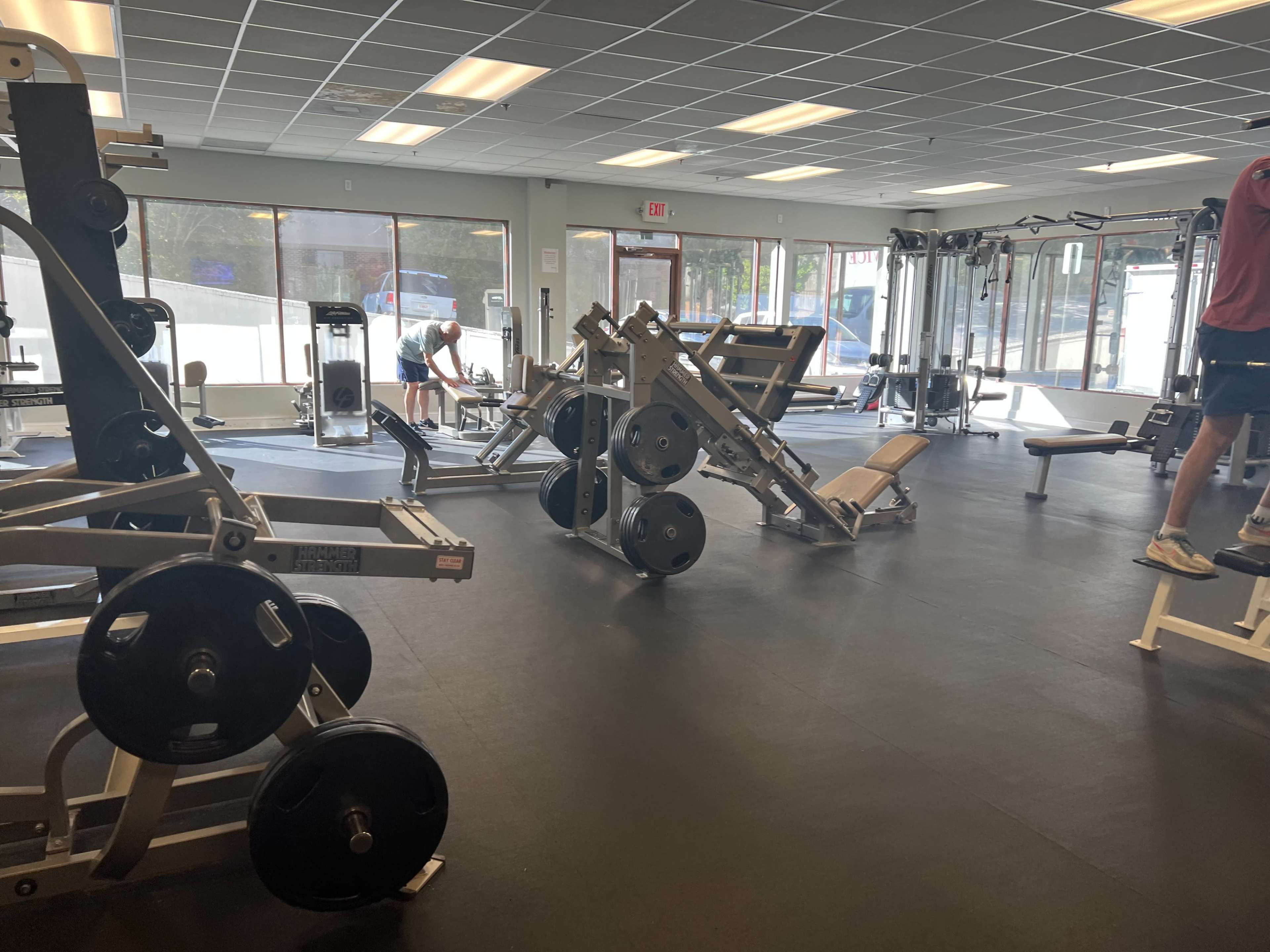 A spacious gym interior with various weightlifting and exercise equipment arranged neatly on the floor.