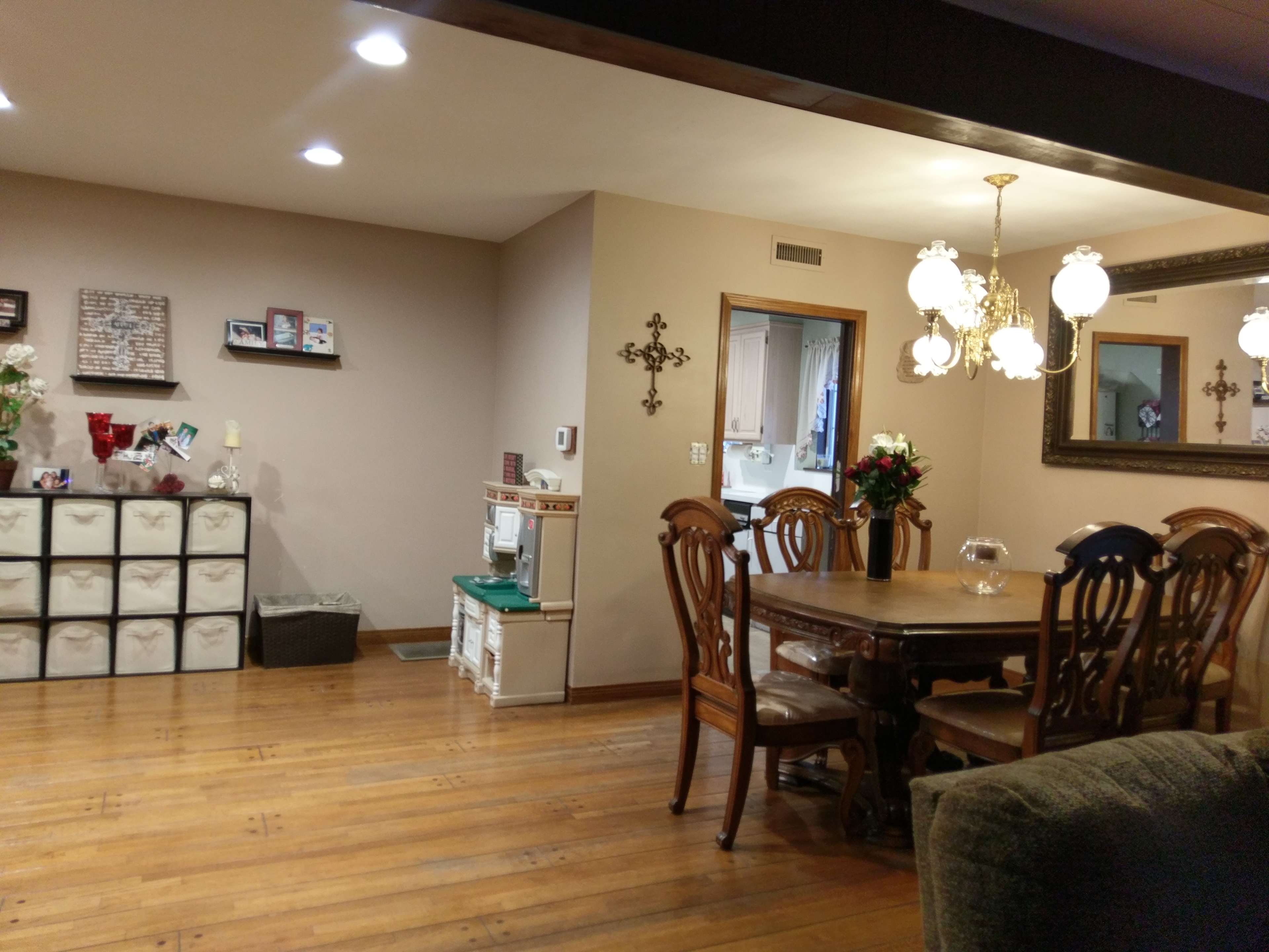 A dining area with a wooden table and chairs, a storage unit, and decorative wall elements in a well-lit room.
