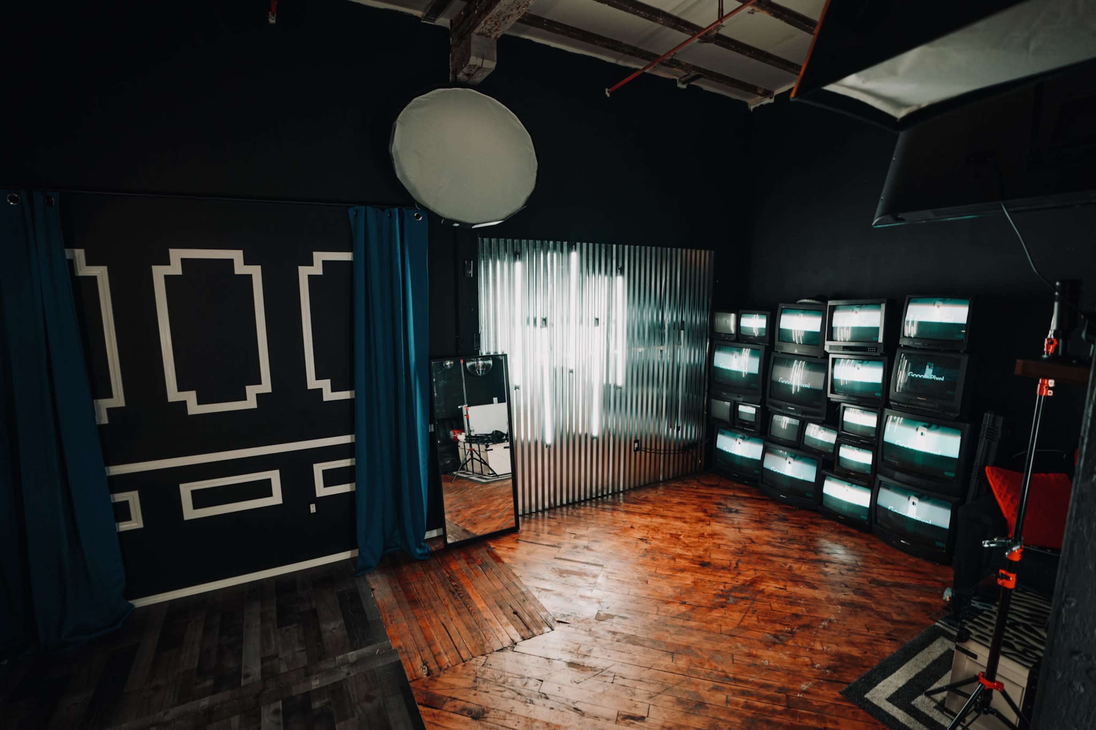 A studio space with dark walls, wooden flooring, and illuminated display cases along one side.