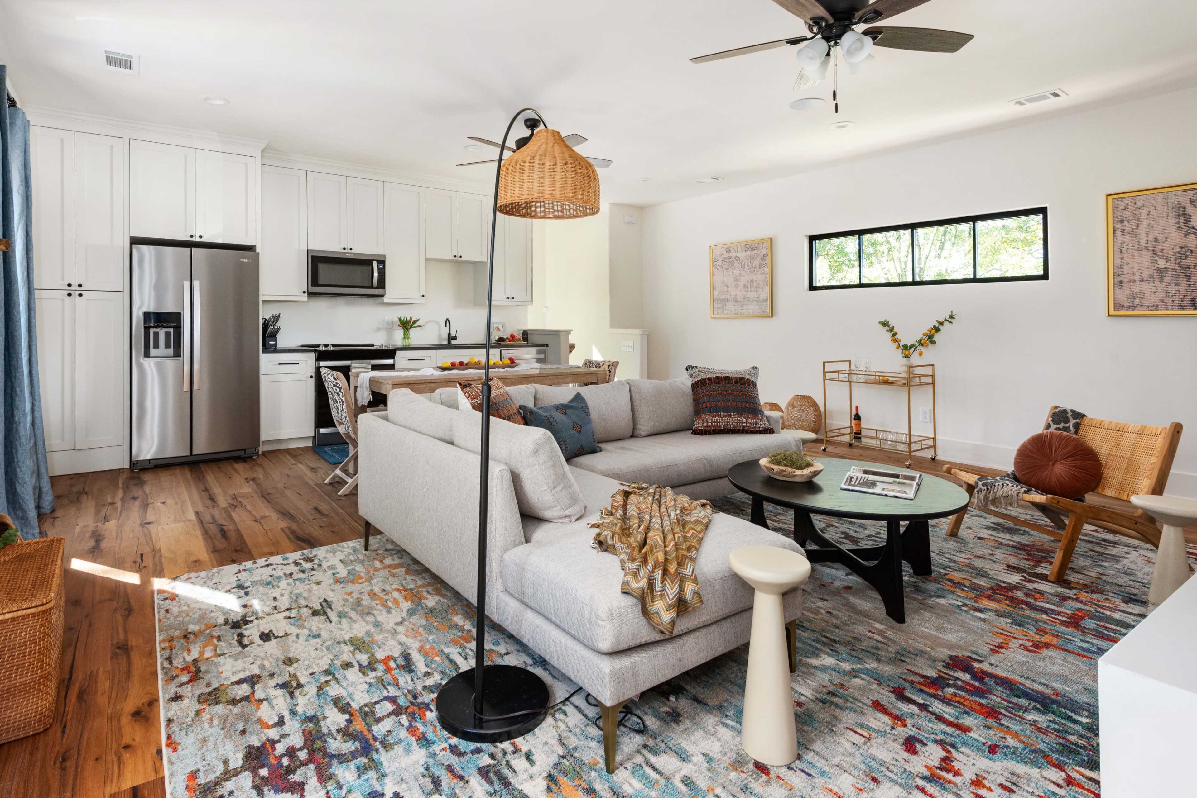 A modern living room showcases a light-colored sectional sofa, a round coffee table, and a mix of decorative elements, including a rug and various seating options.