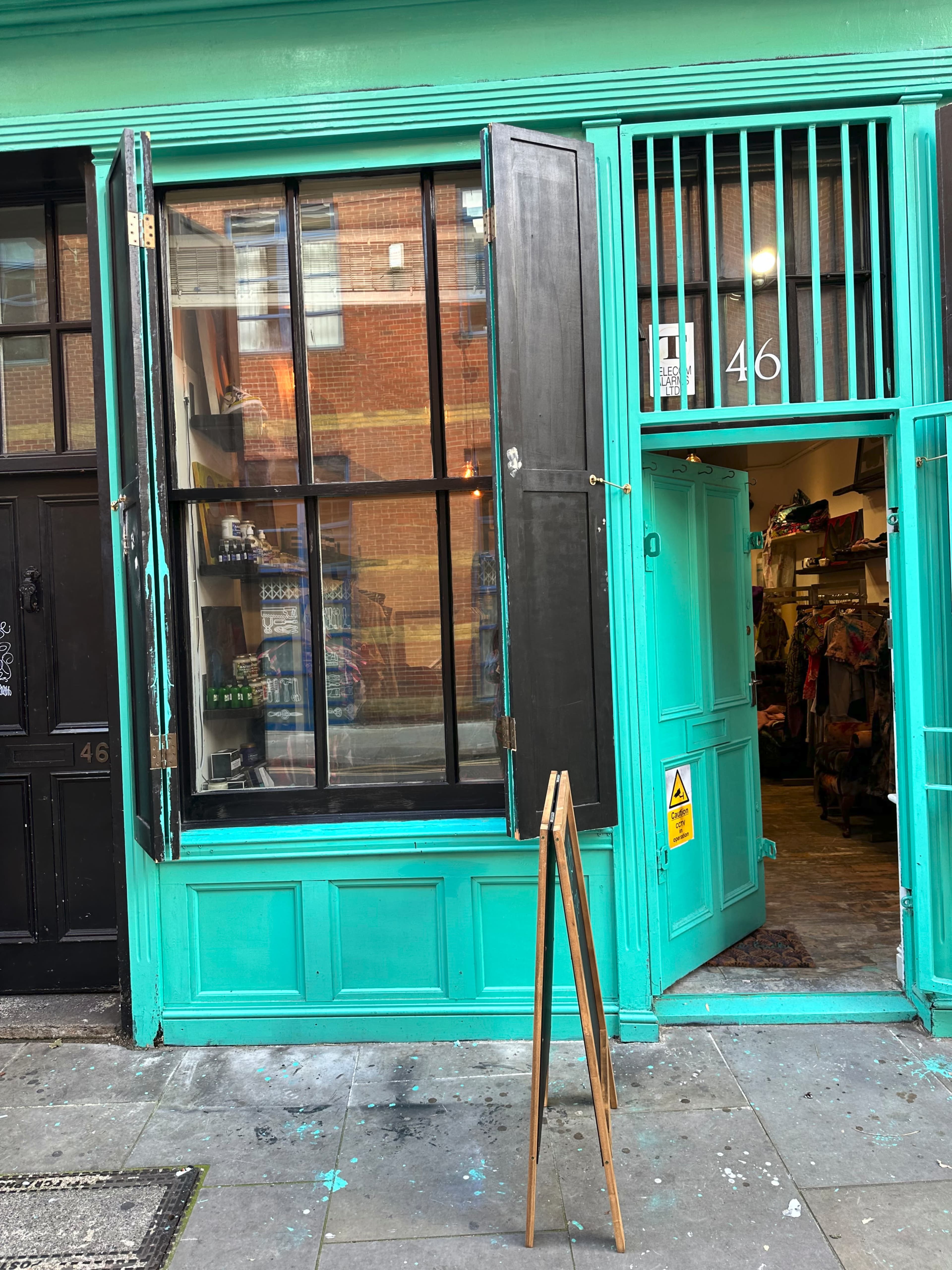 A turquoise storefront with open black windows and an A-frame sign stands at number 146 on a city street.