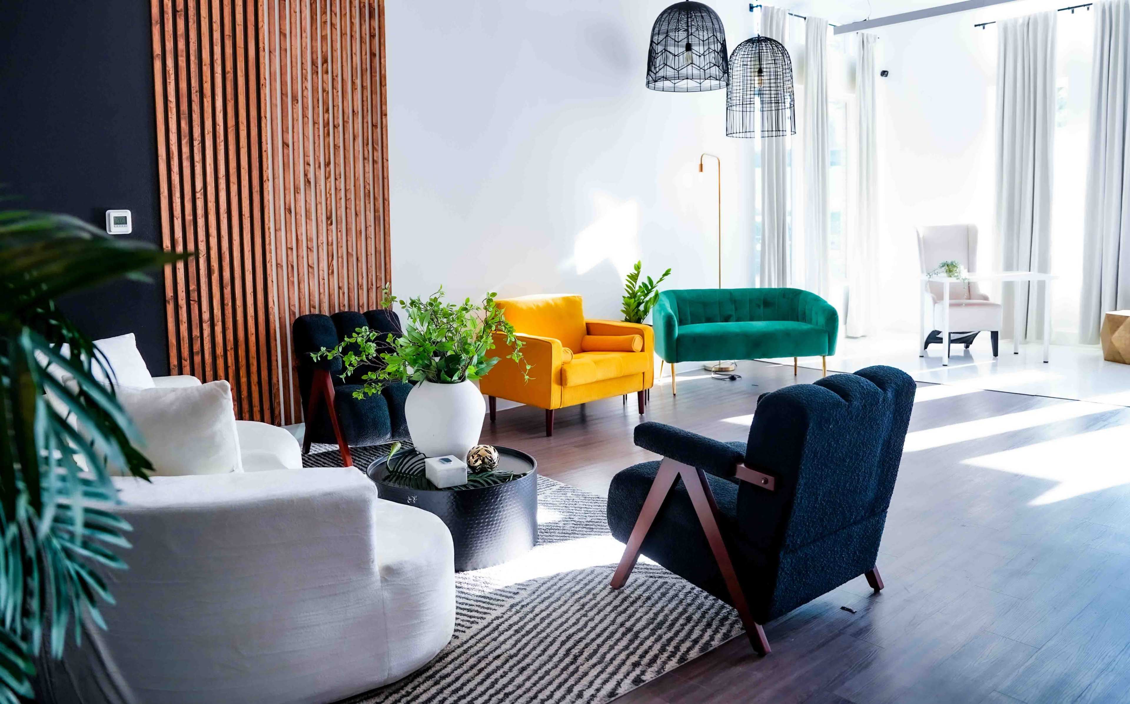 The scene shows a modern living room with a mix of colorful furniture, including a yellow chair and a green sofa, accented by plants and various light fixtures.