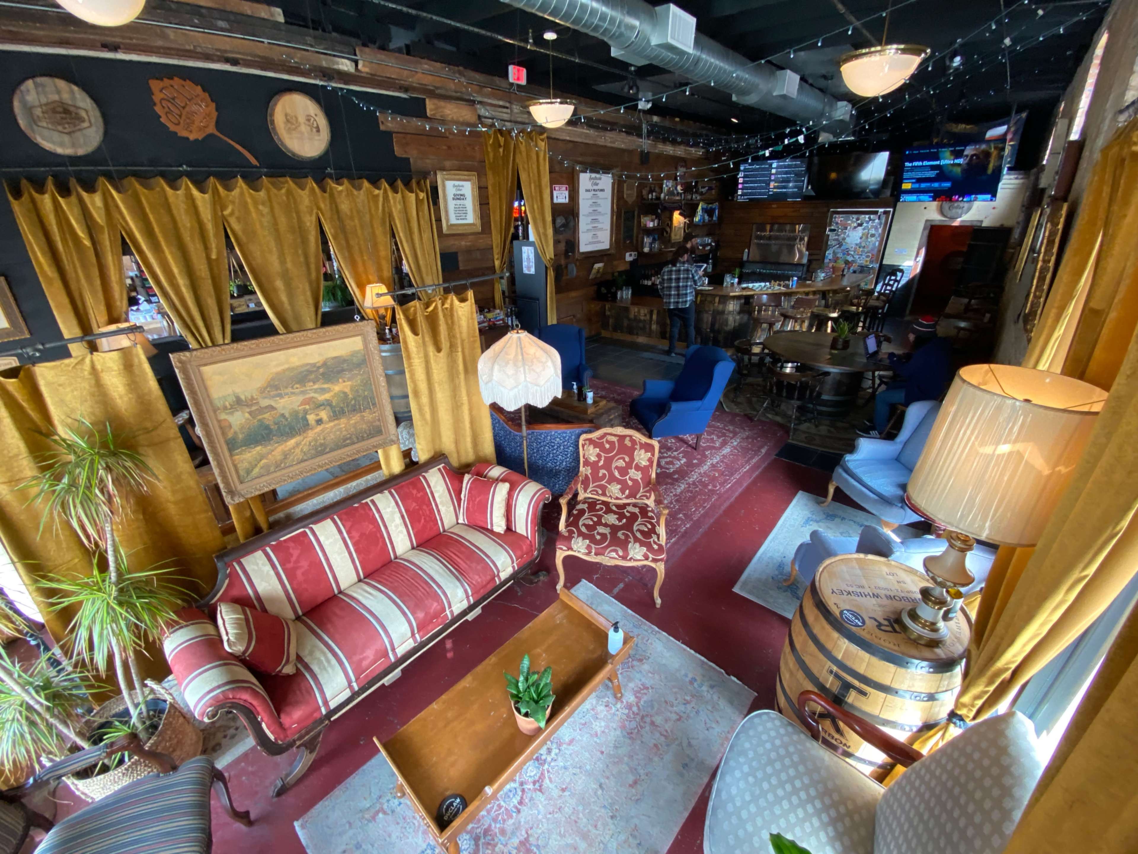 A cozy bar interior with striped and patterned seating, wooden decorations, and warm lighting.