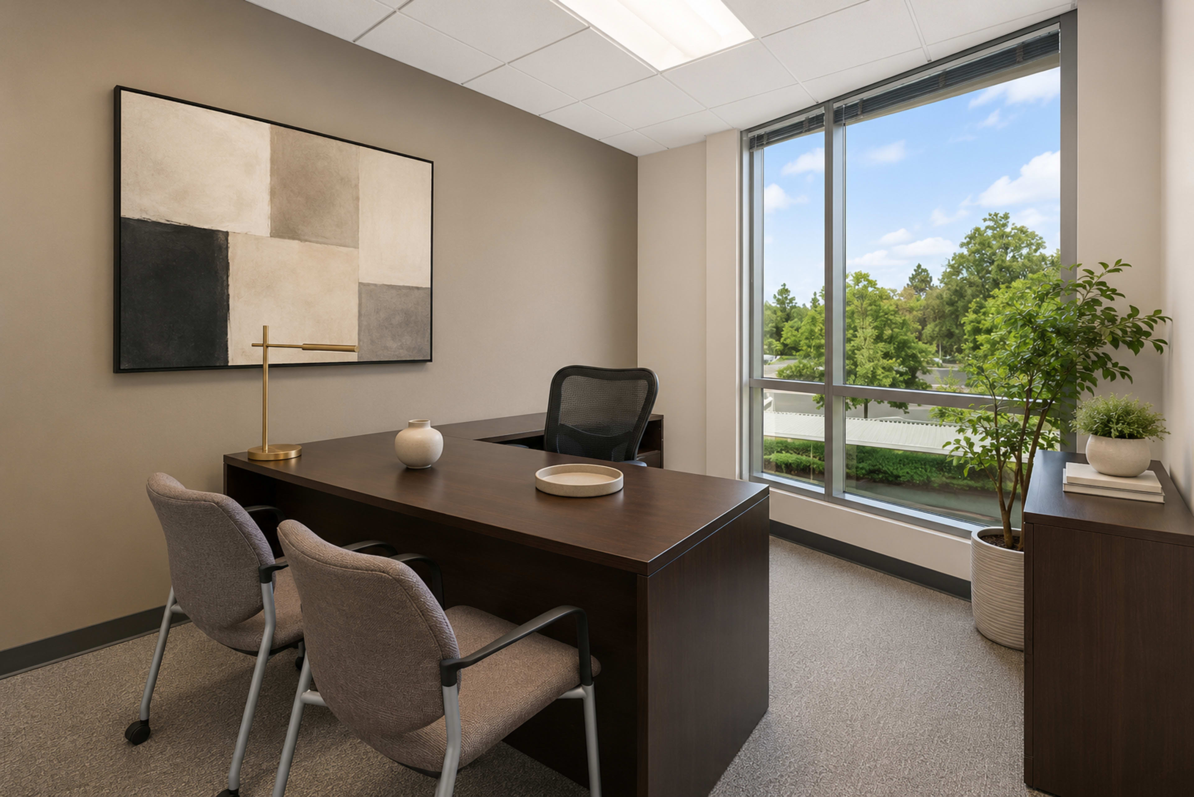 The image shows a modern office space with a brown desk, two chairs, a large window overlooking greenery, and minimalist decor on the walls.
