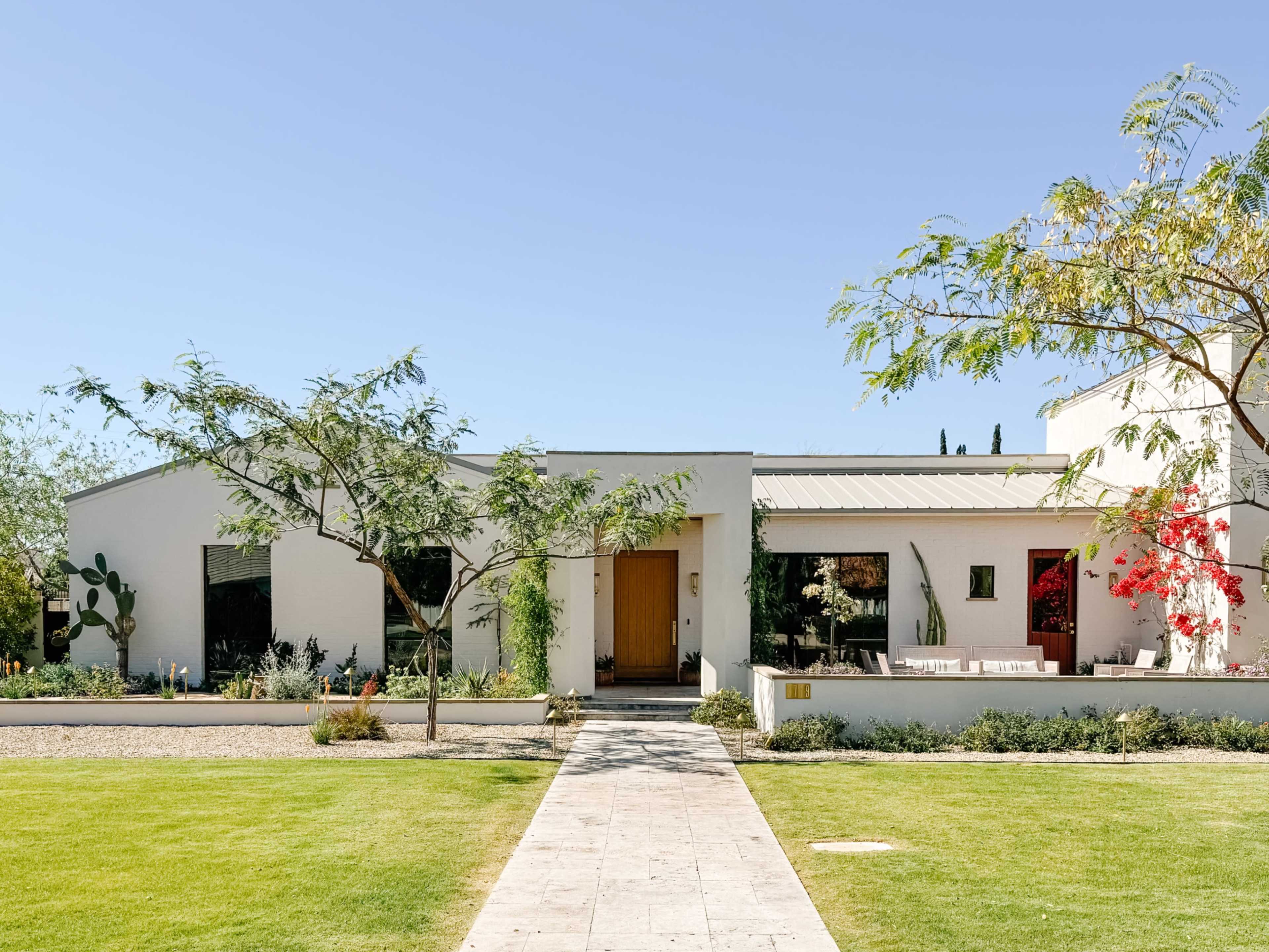 A modern white house with a landscaped front yard and a pathway leading to the entrance.