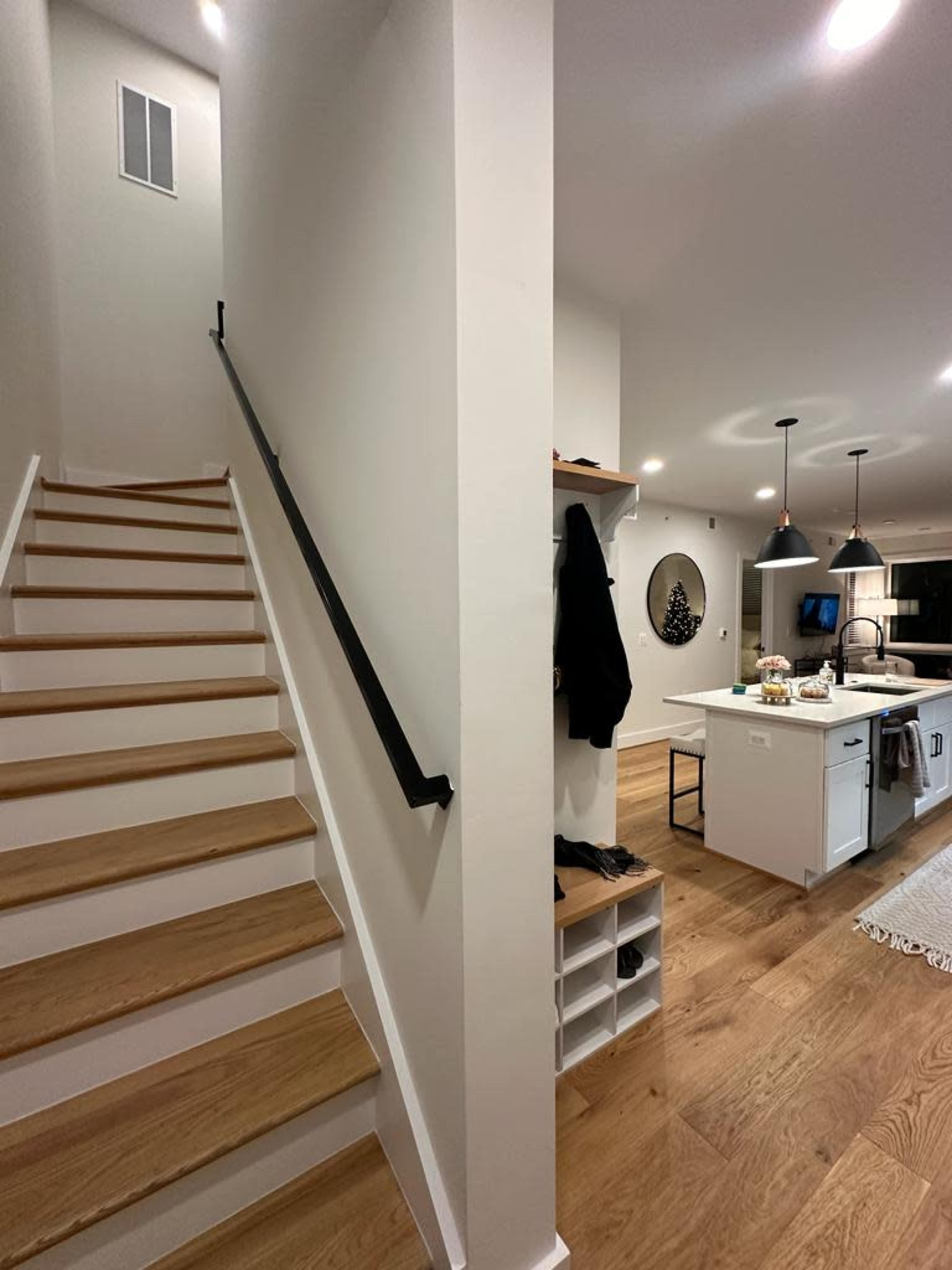 A hallway leading to a staircase on the left and a modern kitchen area on the right.